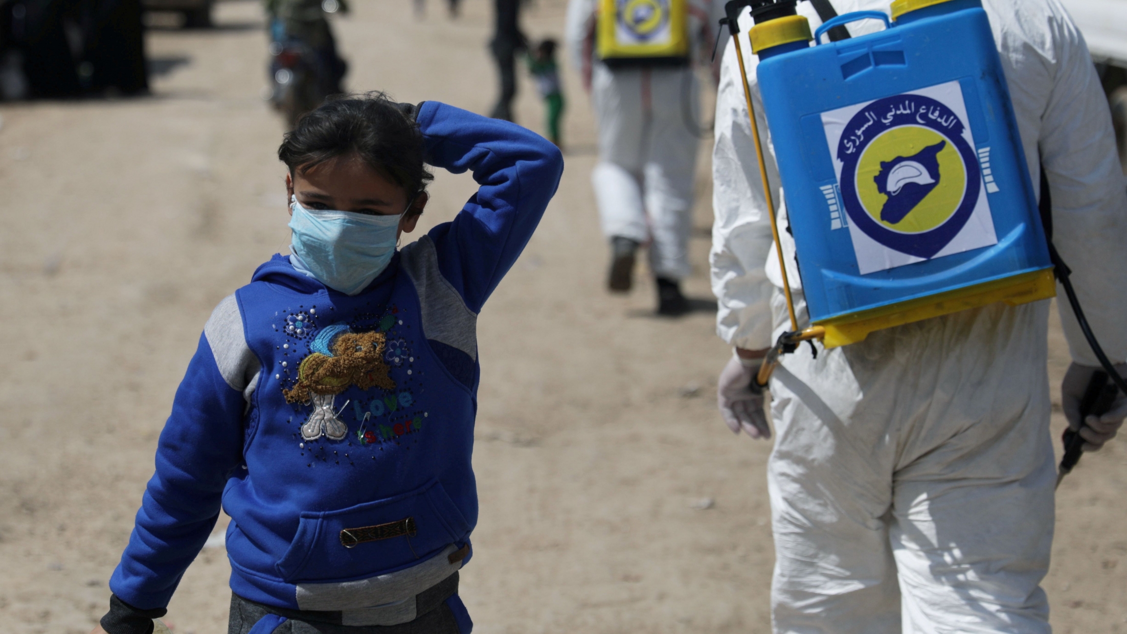 An internally displaced Syrian girl wears a face mask as members of the Syrian Civil defence sanitize the Bab al-Nour internally displaced persons camp, to prevent the spread of the coronavirus (COVID-19) in Azaz, Syria, March 26, 2020. 