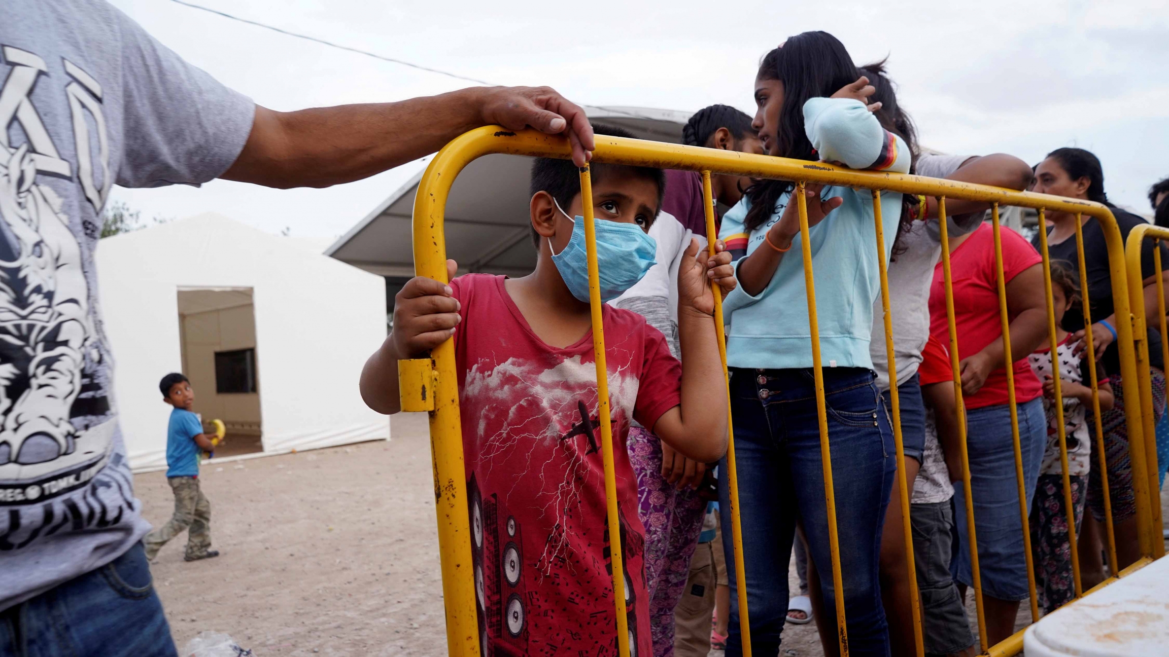 A migrant child, who is seeking asylum in the US, wears a protective mask as he stands in line for food, amid an outbreak of the coronavirus disease (COVID-19), in the migrant camp of Matamoros, Mexico, April 1, 2020. A migrant child, who is seeking asylum in the US, wears a protective mask as he stands in line for food, amid an outbreak of the coronavirus disease (COVID-19), in the migrant camp of Matamoros, Mexico, April 1, 2020.