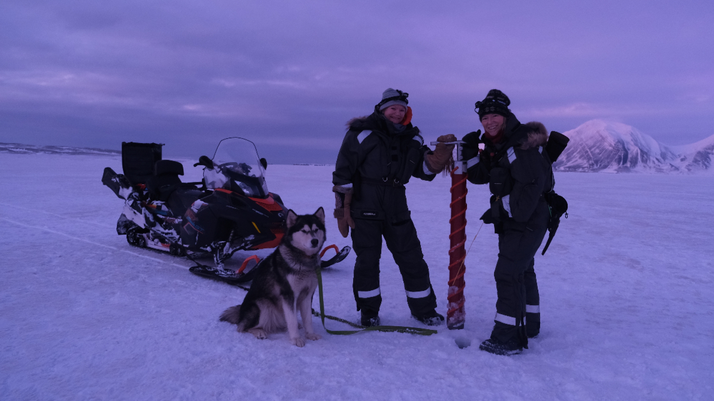 Sunniva Sorby and Hilde Fålulm Strøm in Svalbard, Norway. two women pose for a photo with a dog in the snow.
