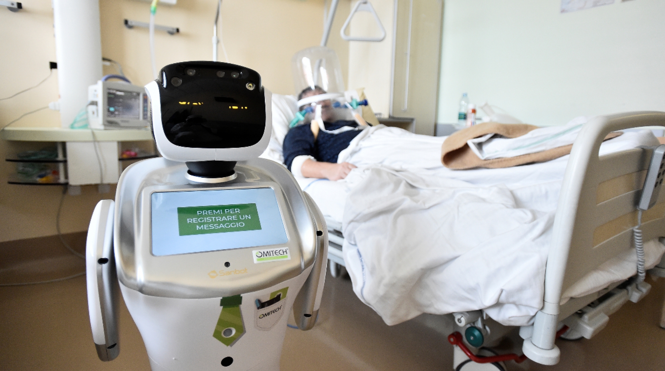 Tommy, the robot nurse. A picture of a robot in a hospital room and a patient laying on the bed sick.