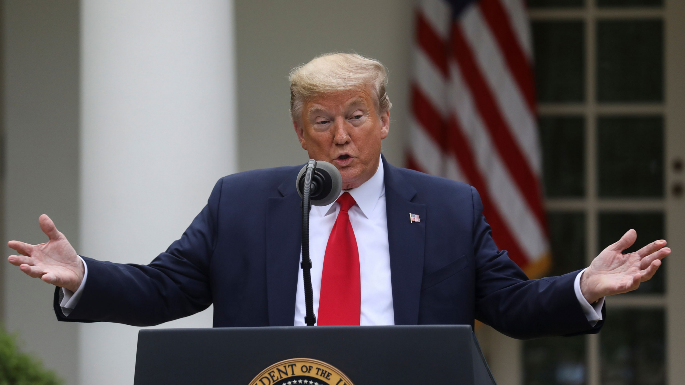 US President Donald Trump addresses the daily coronavirus task force briefing at the White House, April 14, 2020. US President Donald Trump is shown standing at a podium with both of his arms outstretched.
