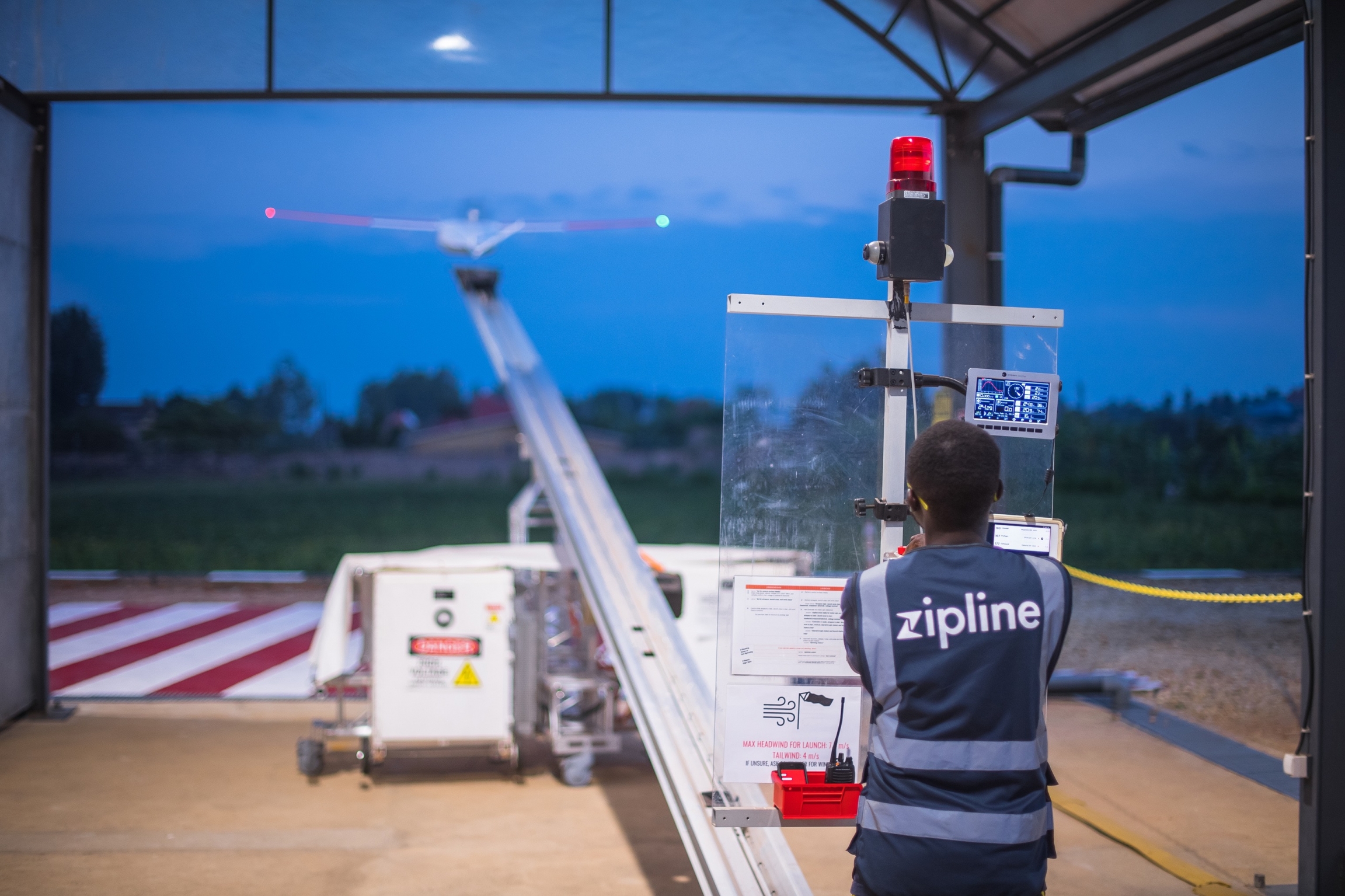 Zipline drones use a launcher to start the flight. a man looks at a drone flying.