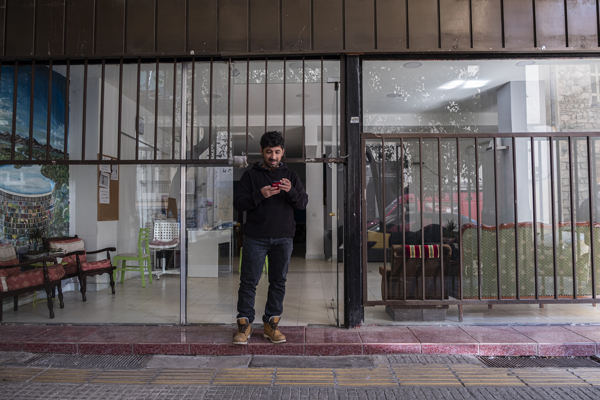 Arash Hampay smokes in front of Cafe Patogh before the volunteers arrive to start packing and distributing the "hope bags" in Athens, Greece. Arash Hampay smokes in front of Cafe Patogh before the volunteers arrive to start packing and distributing the "hope bags" in Athens, Greece.