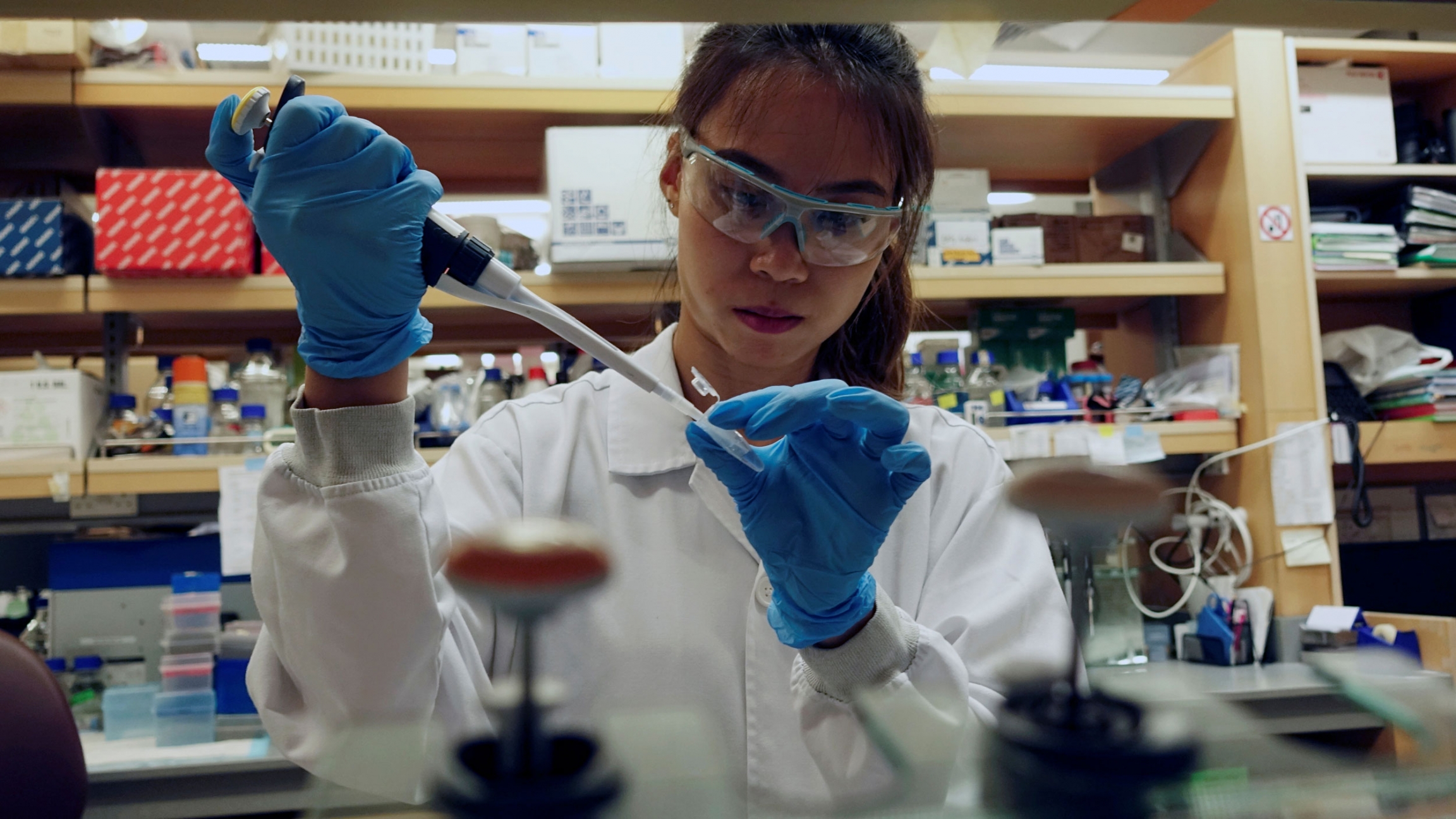 A researcher works in a lab at the Duke-NUS Medical School, which is developing a way to track genetic changes that speed testing of vaccines against the coronavirus disease in Singapore, March 2020. A researcher is shown holding a dropper up to a vial while wearing medical protective clothing.