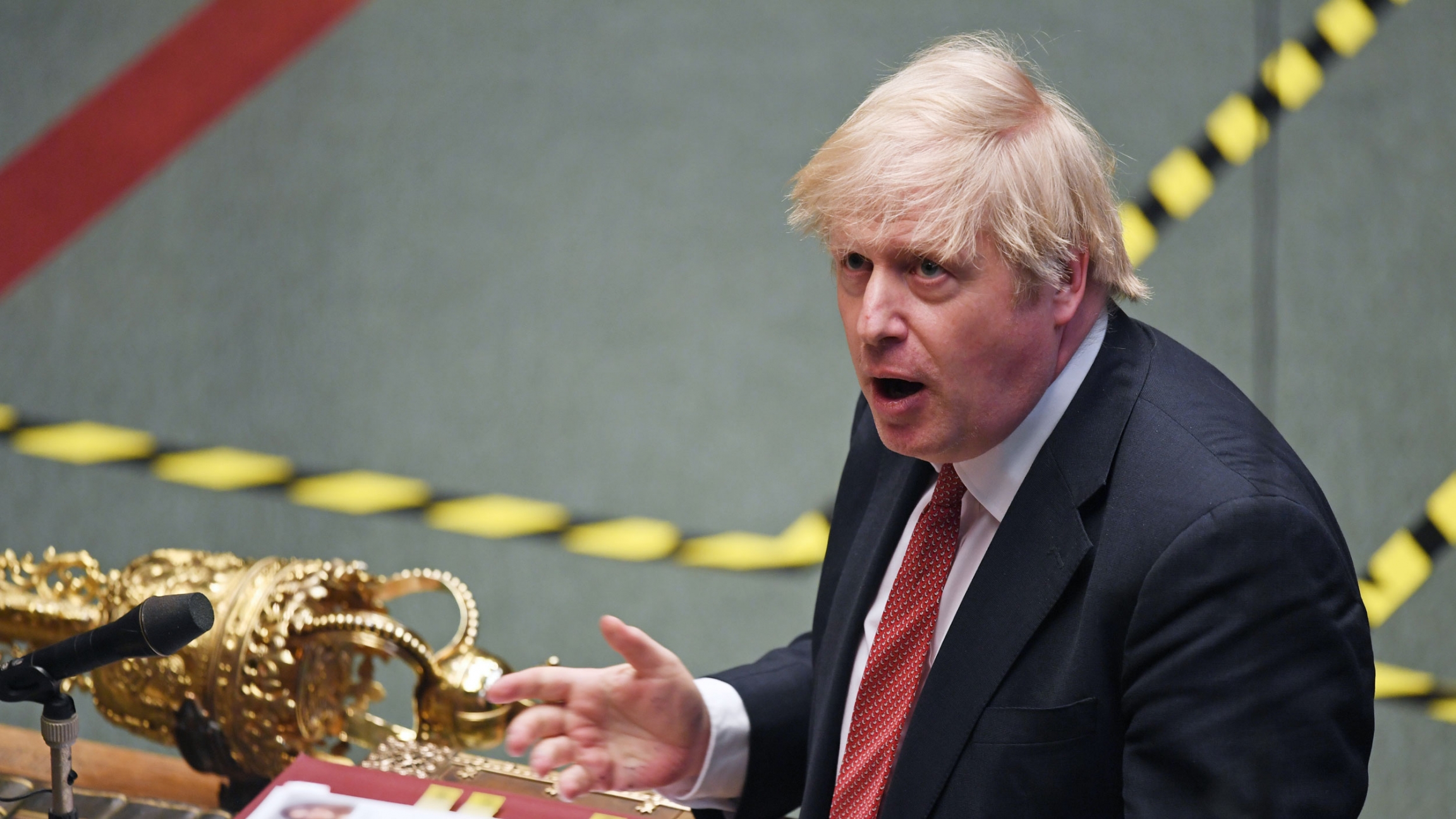 Britain's Prime Minister Boris Johnson speaks during a parliament session amid the coronavirus outbreak in London, Britain, May 11, 2020. Britain's Prime Minister Boris Johnson is shown in a photograph from above standing at a podium with his hand outstretched.
