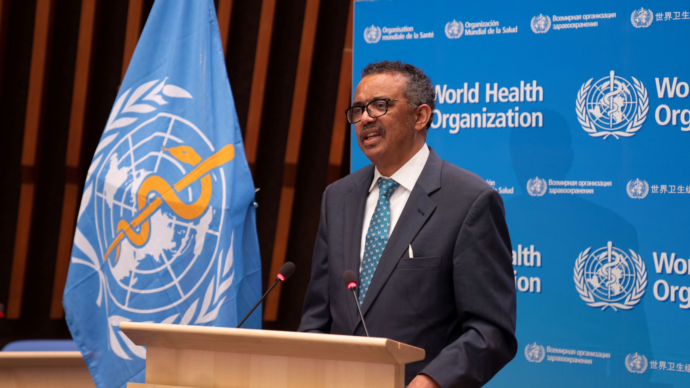 Tedros Adhanom Ghebreyesus, director general of World Health Organization speaks at the virtual 73rd World Health Assembly following the coronavirus outbreak in Geneva, Switzerland, May 18, 2020. Tedros Adhanom Ghebreyesus is shown standing at a wooden podium with the blue WHO flag next to him.