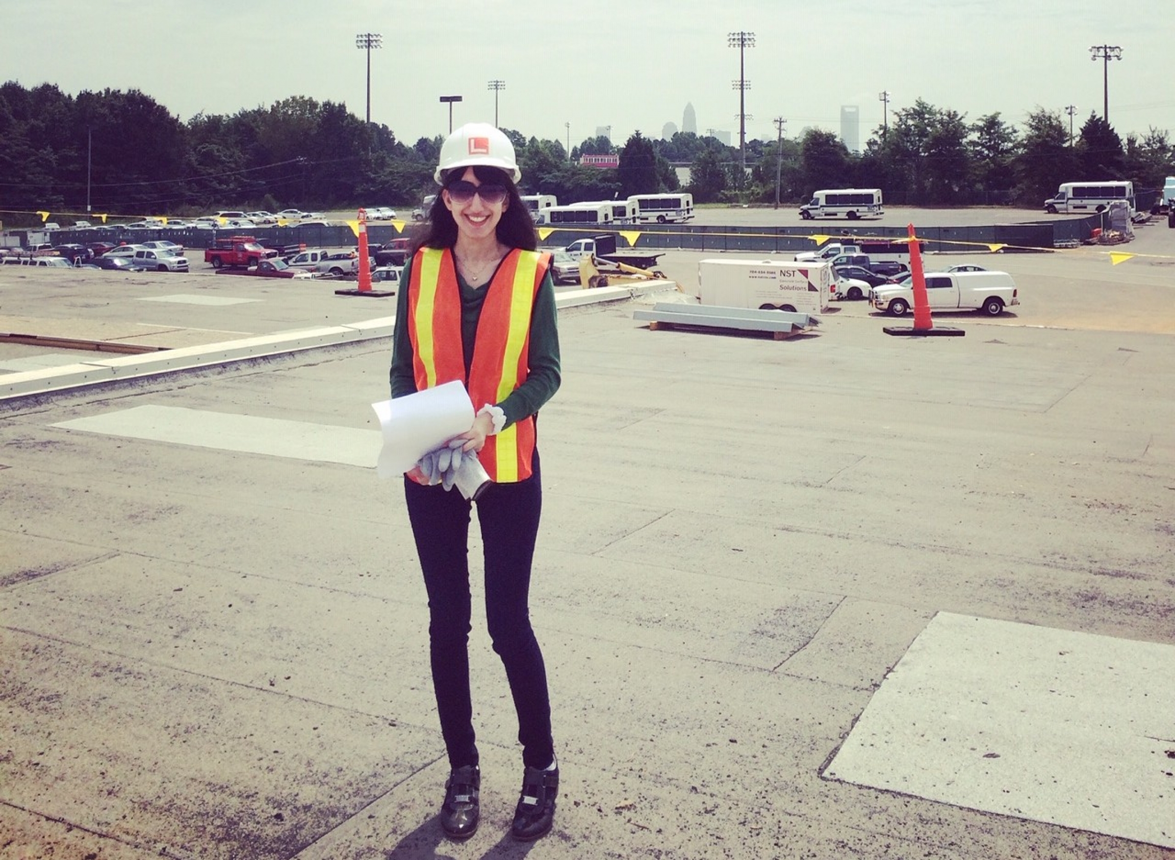 A woman with construction vest and hat standing on a structure