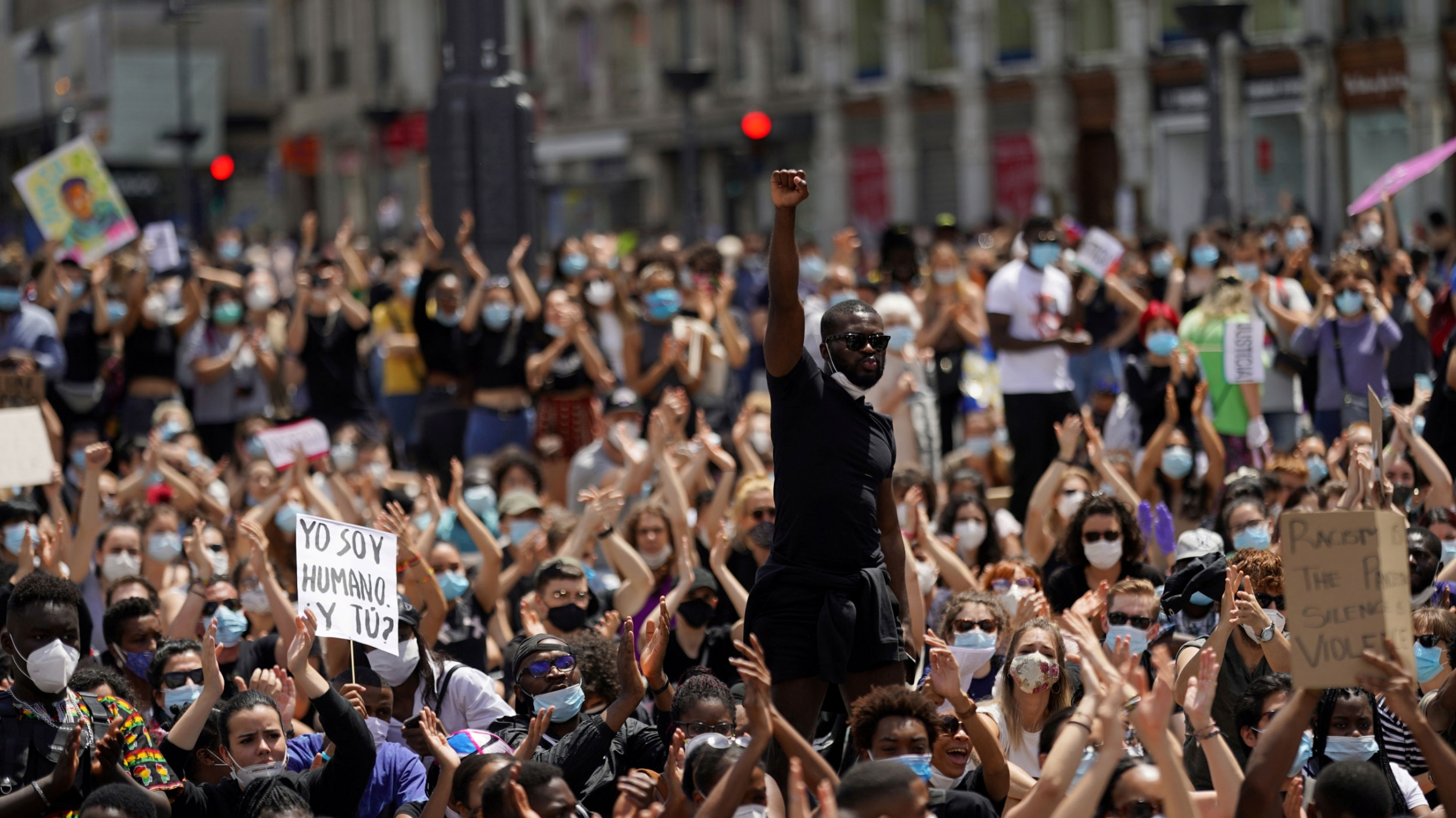A man raises his fist over a crowd of demonstrators during a protest against racial inequality in the aftermath of the death in Minneapolis police custody of George Floyd, at Puerta del Sol square in Madrid, Spain, June 7, 2020. A large group of people are shown in a crowd with man in the middle raising his right fist in the air.