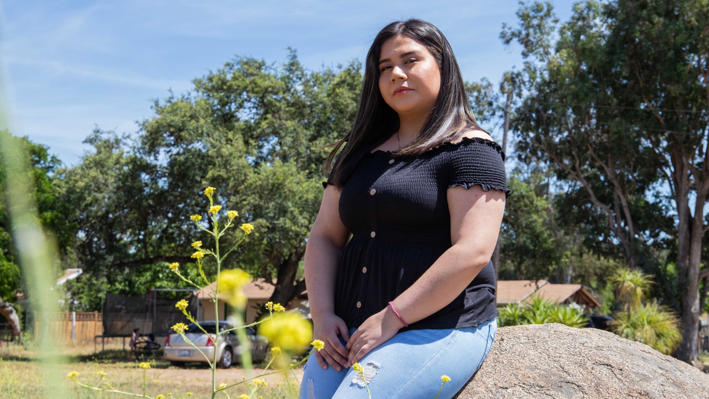 Marlene Herrera is an undecided voter in California, a state where Latinos overwhelmingly support Vermont Sen. Bernie Sanders, who recently dropped out of the presidential race. A young woman wearing a black top sits in fronto of a house for a photo.