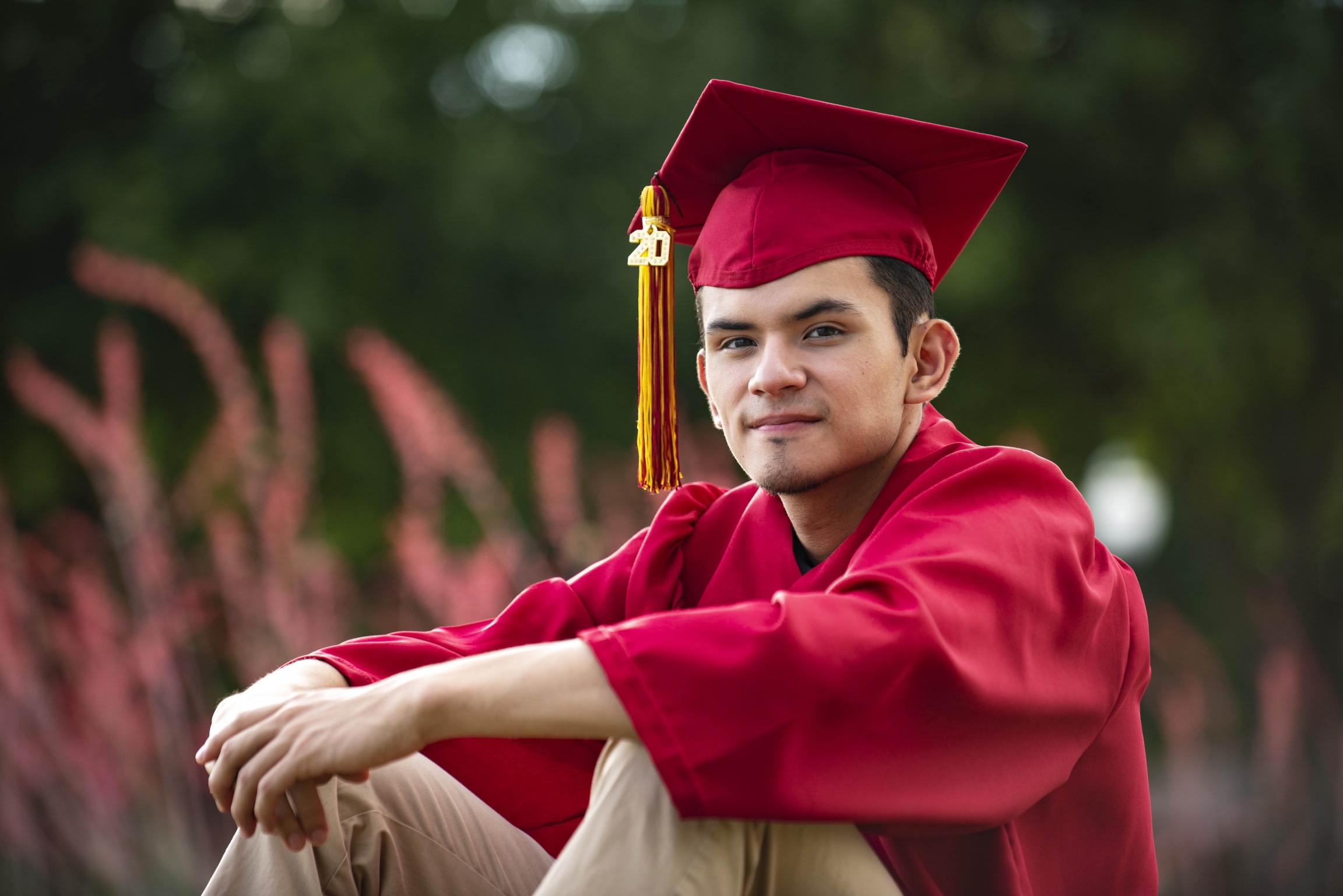 Izcan Ordaz, who describes himself as more of a centrist in politics, says Texas conservatism has influenced him. He says his parents are more liberal than he is. Nearly 40% of Texas’ population is Latino, and about one in three eligible voters is Latino. A young man wears a red graduation gown, cap and tassel.