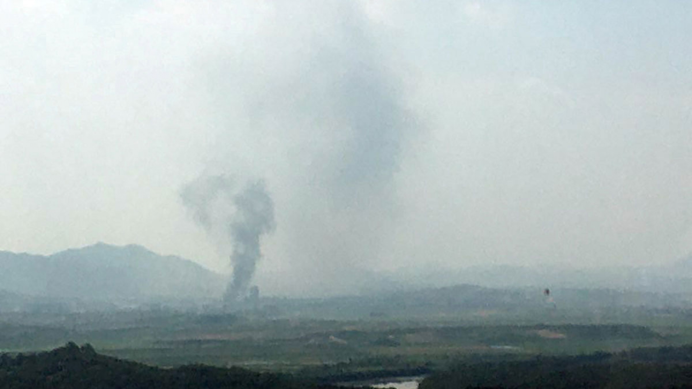 A smoke rises from Kaesong Industrial Complex in this picture taken from the south in Paju, South Korea, June 16, 2020. A grainy photograph showing smoke rising in the distance from a destroyed building.