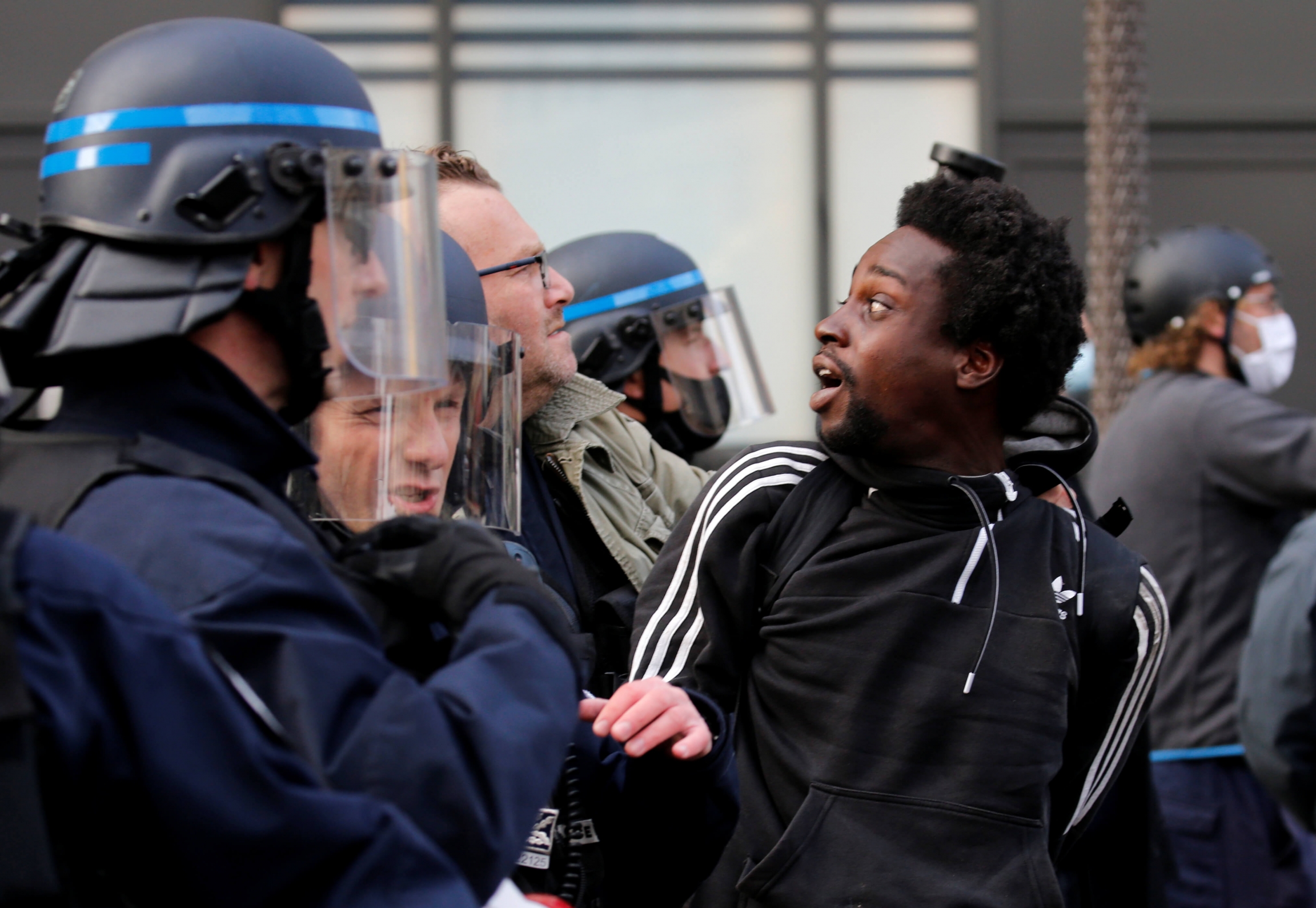 A protester is detained during a banned demonstration in memory of Adama Traoré, a 24-year-old black Frenchman who died in a 2016 police operation which some have likened to the killing of George Floyd in the United States, on the Place de la Republique i A black Frenchman wearing sweatshirt is detained by a uniformed police offer in France