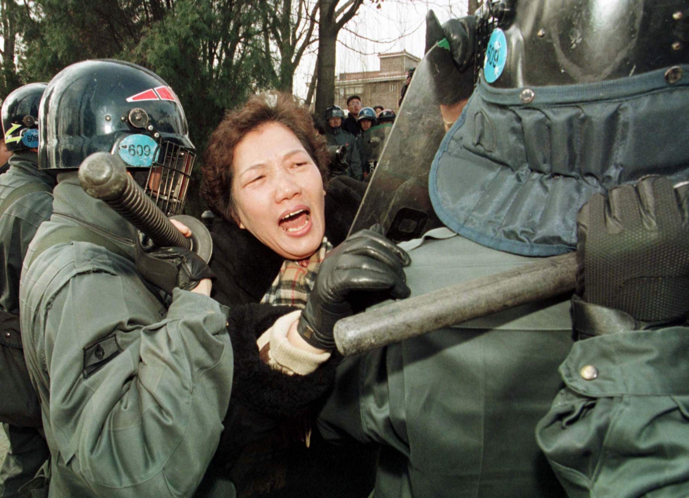 South Korean woman Bae Un-shim, whose son was killed by police in 1987 under then-president Chun Doo-hwan, screams at riot police in an attempt to break through their cordon to reach the limousine carrying former president Chun, who was given a special go A woman protester cries out amid riot police in green uniforms.