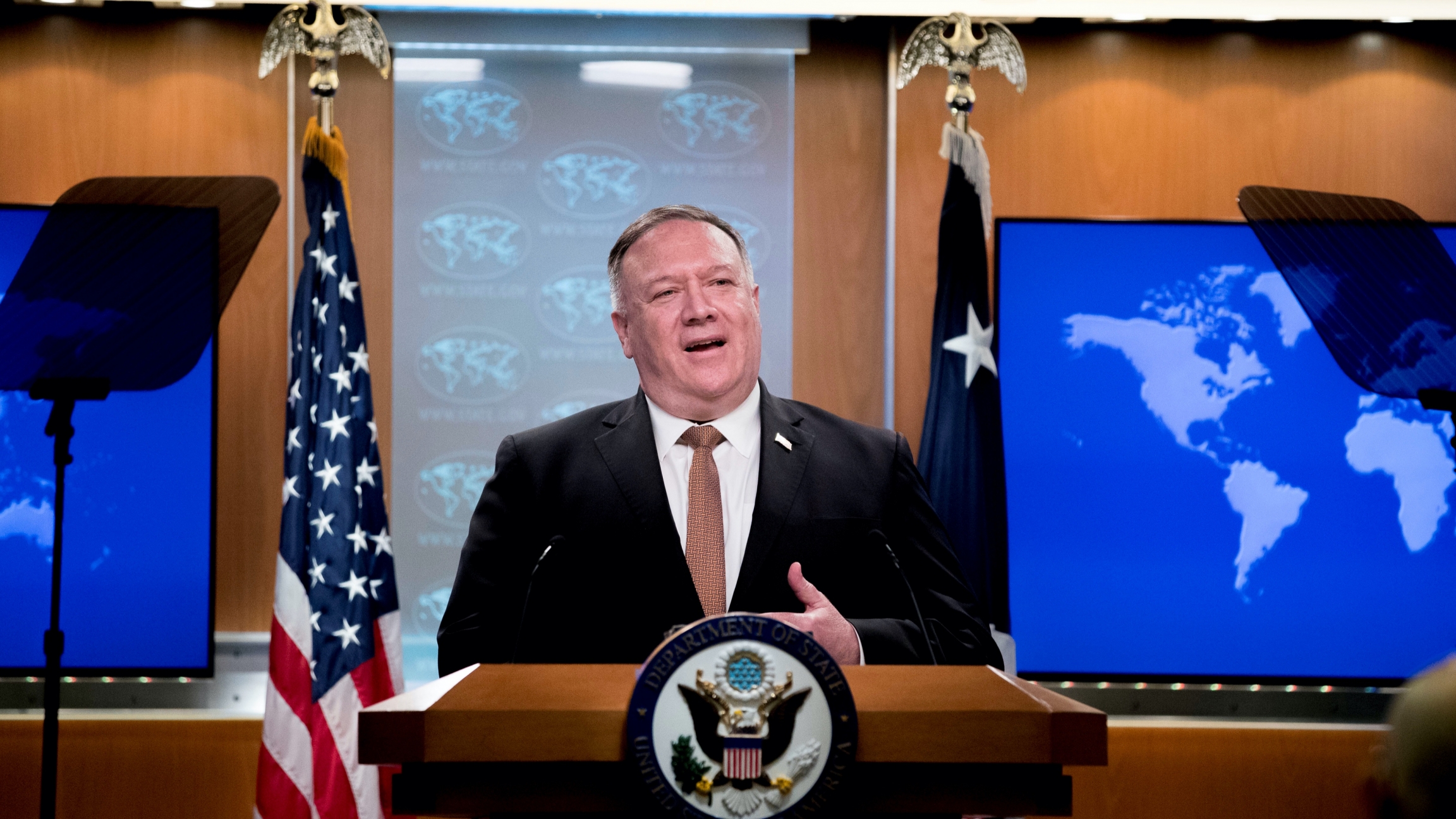 US Secretary of State Mike Pompeo speaks during a news conference at the State Department in Washington, DC, July 15, 2020. A man wearing a suit stands at a State Department podium between two flags