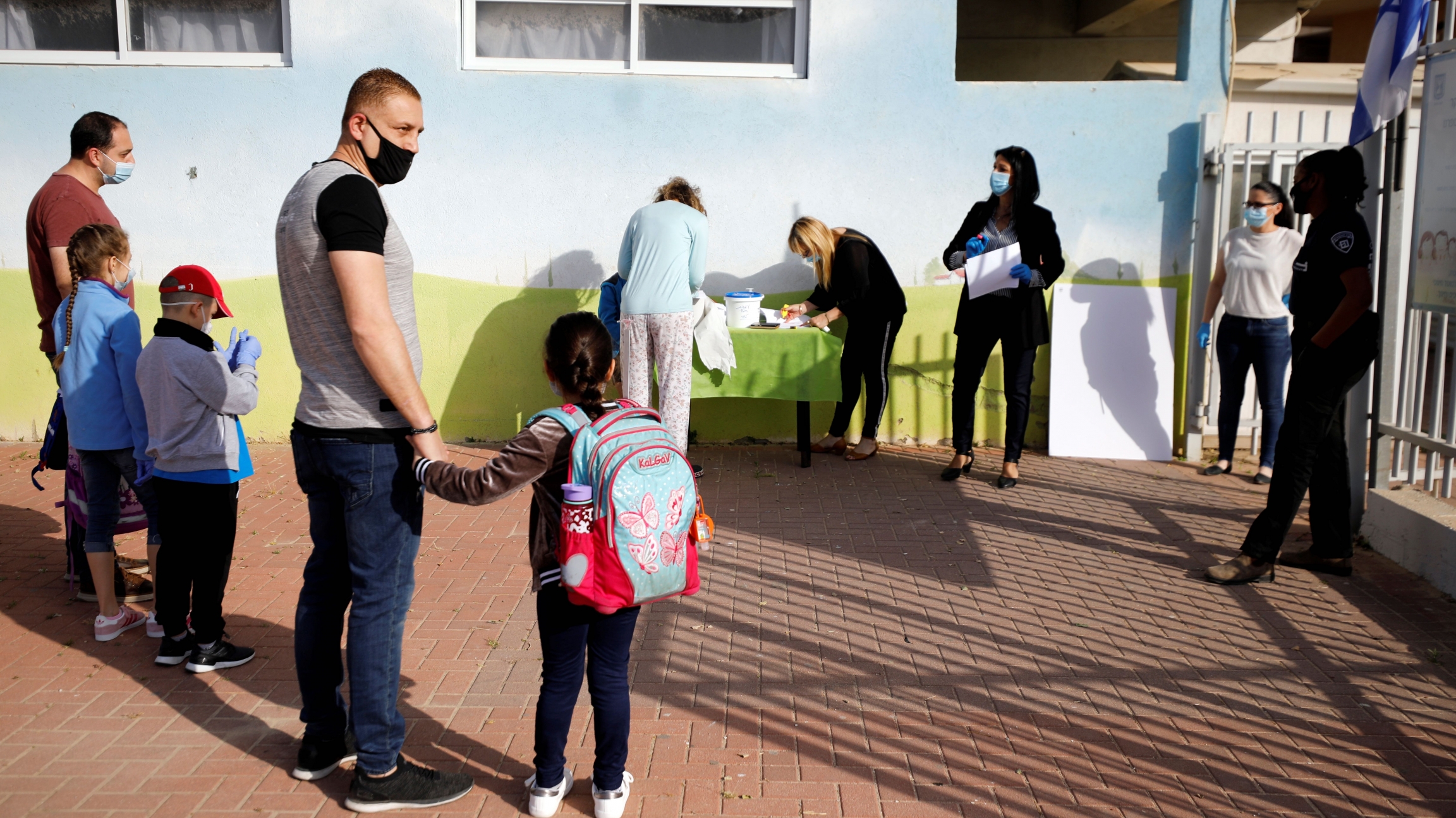 Parents wait with their children to enter their elementary school in Sderot as it reopens following the ease of restrictions preventing the spread of the coronavirus in Israel, May 3, 2020. Parents wait with their children to enter their elementary school in Sderot as it reopens following the ease of restrictions preventing the spread of the coronavirus in Israel, May 3, 2020.