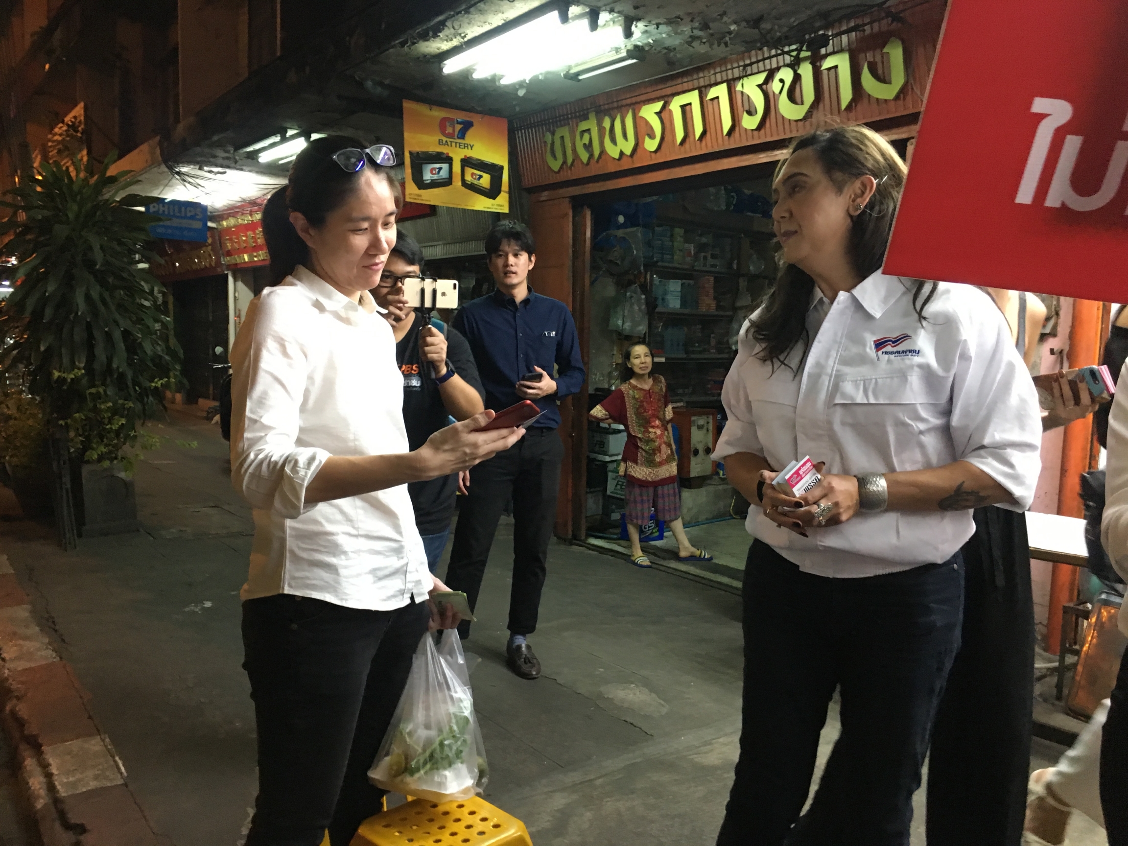 Pauline Ngarmpring, Thailand's first transgender candidate for prime minister, hands a name card to a vendor as she campaigns in the market in Khlong Toey, Bangkok, Feb. 27, 2019.