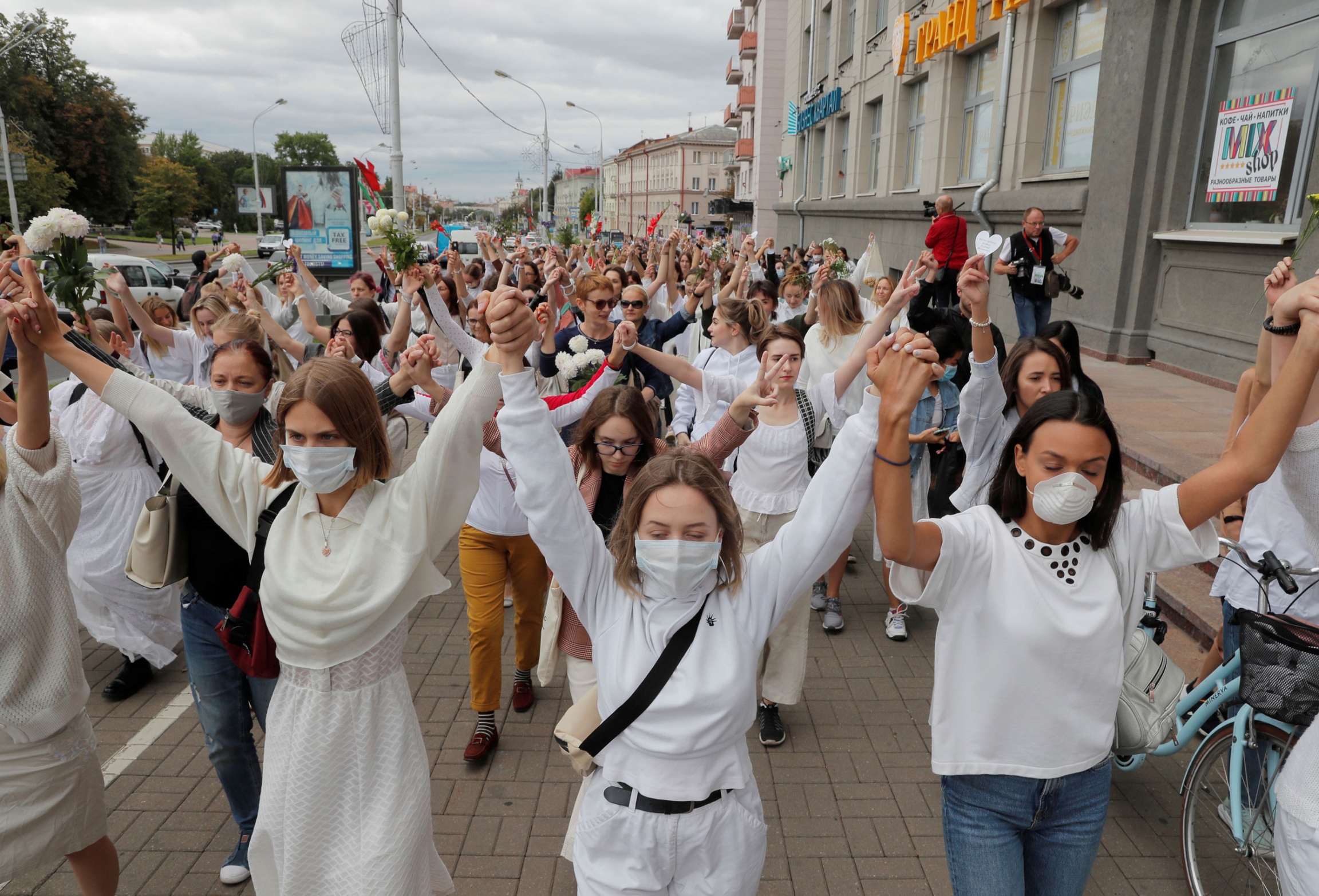 Women take part in a demonstration against police violence during the recent rallies of opposition supporters following the presidential election in Minsk, Belarus, August 12, 2020. A large crowd of women are shown wearing white and holding their hands in the air.
