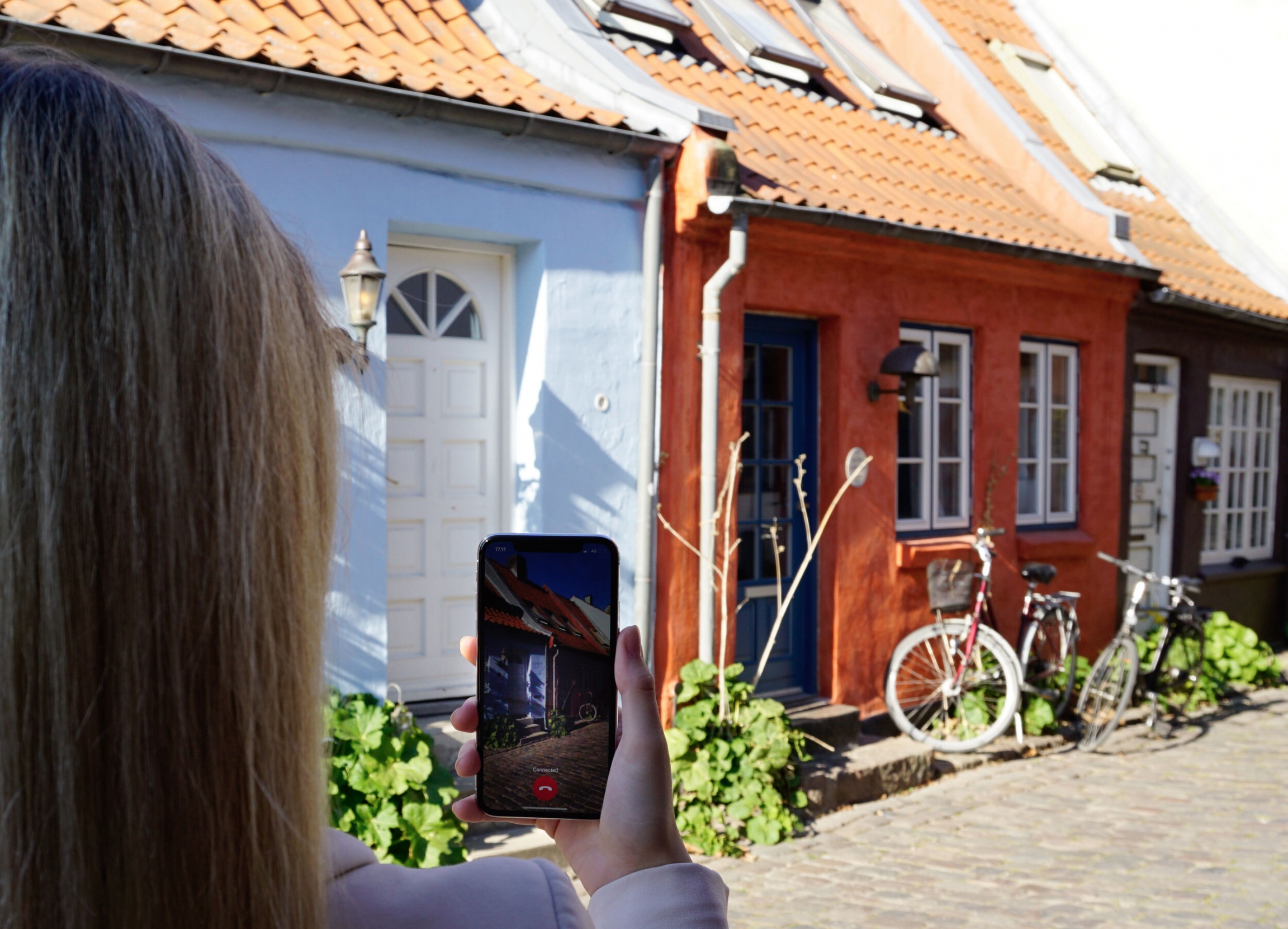A woman uses Be My Eyes video chat app to connect with a sighted volunteer. A woman uses Be My Eyes video chat app to connect with a sighted volunteer to show a house on a cobblestone street.