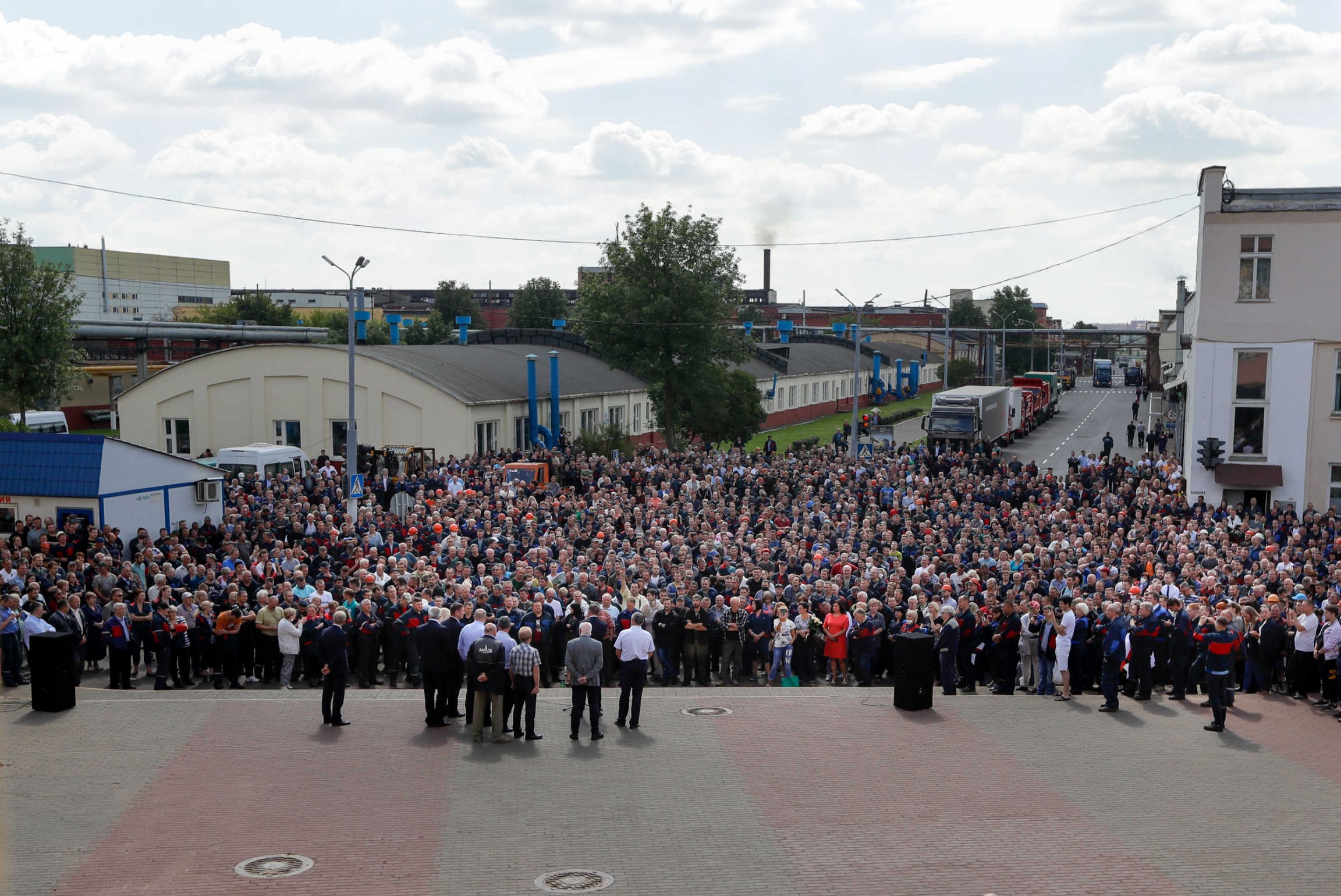Workers gather during a rally at the Minsk Automobile Plant in Minsk, Belarus, Aug. 14, 2020. A large crowd of people are shown in the street with a factory in the background.