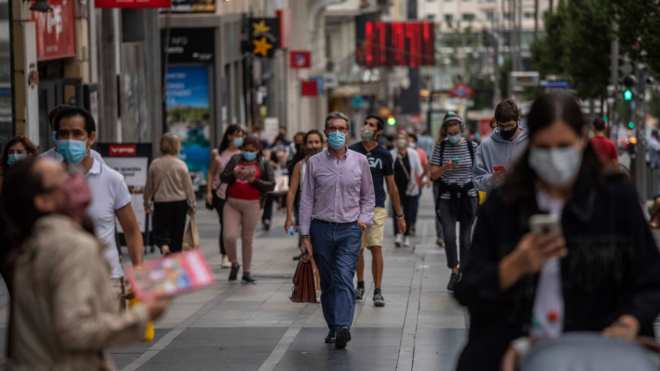 Pedestrians wearing face masks to prevent the spread of coronavirus walk in downtown Madrid, Spain, Sept. 17, 2020. With a coronavirus caseload above 600,000 and more than 30,000 confirmed deaths, Spain has been the hardest hit European country in the sec Dozens of people are show walking around a shopping district and wearing face masks in Madrid, Spain.