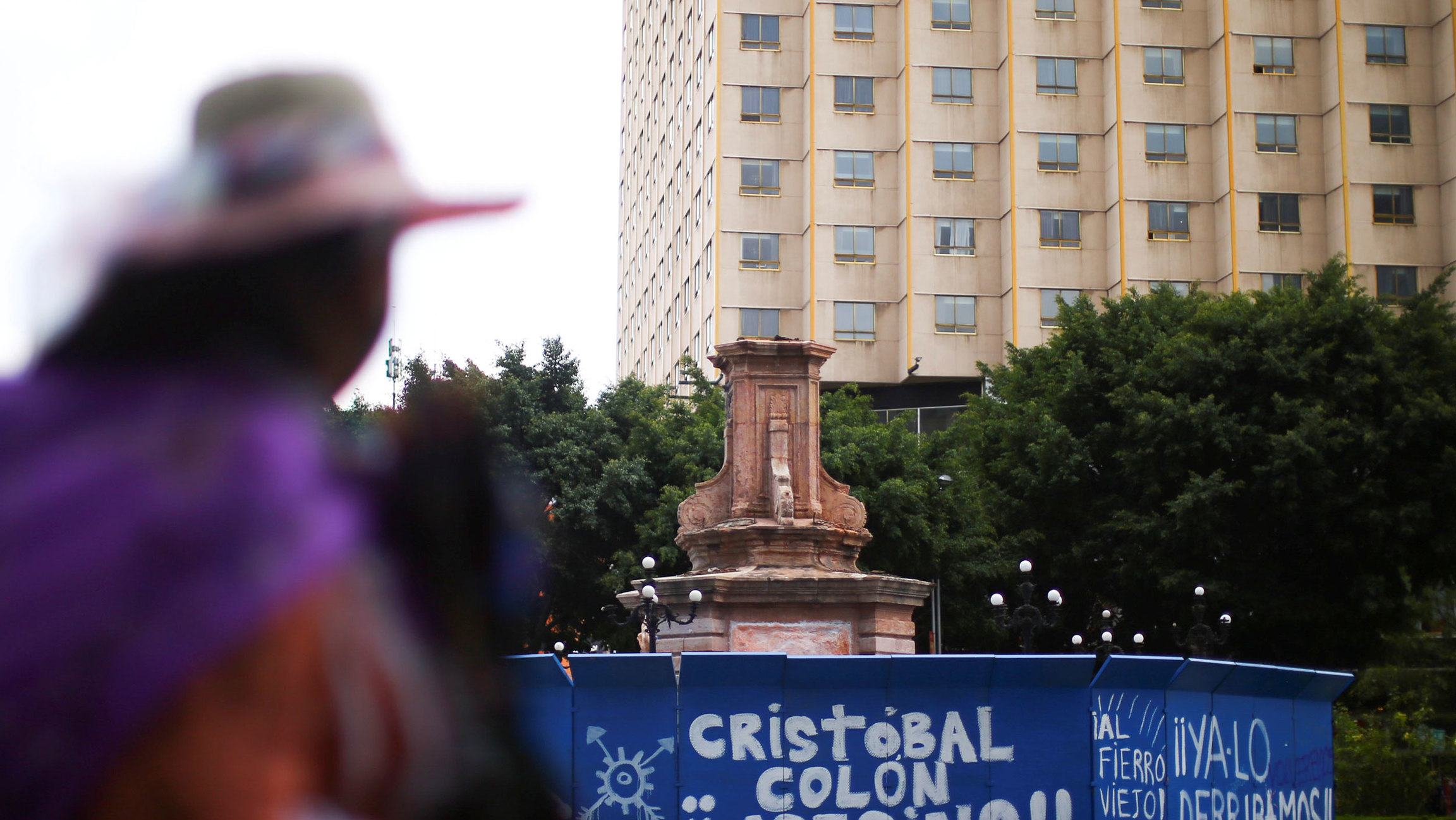 An empty pedestal where a statue of explorer Christopher Columbus, used to stand before it was taken off by the municipality in Mexico City, Mexico, Oct. 12, 2020. A large stone pedestal is shown with the statue of Christopher Columbus removed and a person in the near ground looking on in soft focus.