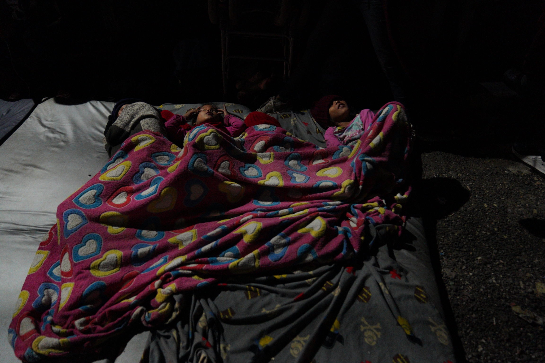 Migrants sleep on a sidewalk in Pamplona Colombia, on Sept. 30. The town had four shelters but local authorities ordered them to shut down to limit large gatherings. A family sleeps in a blanket on the street.