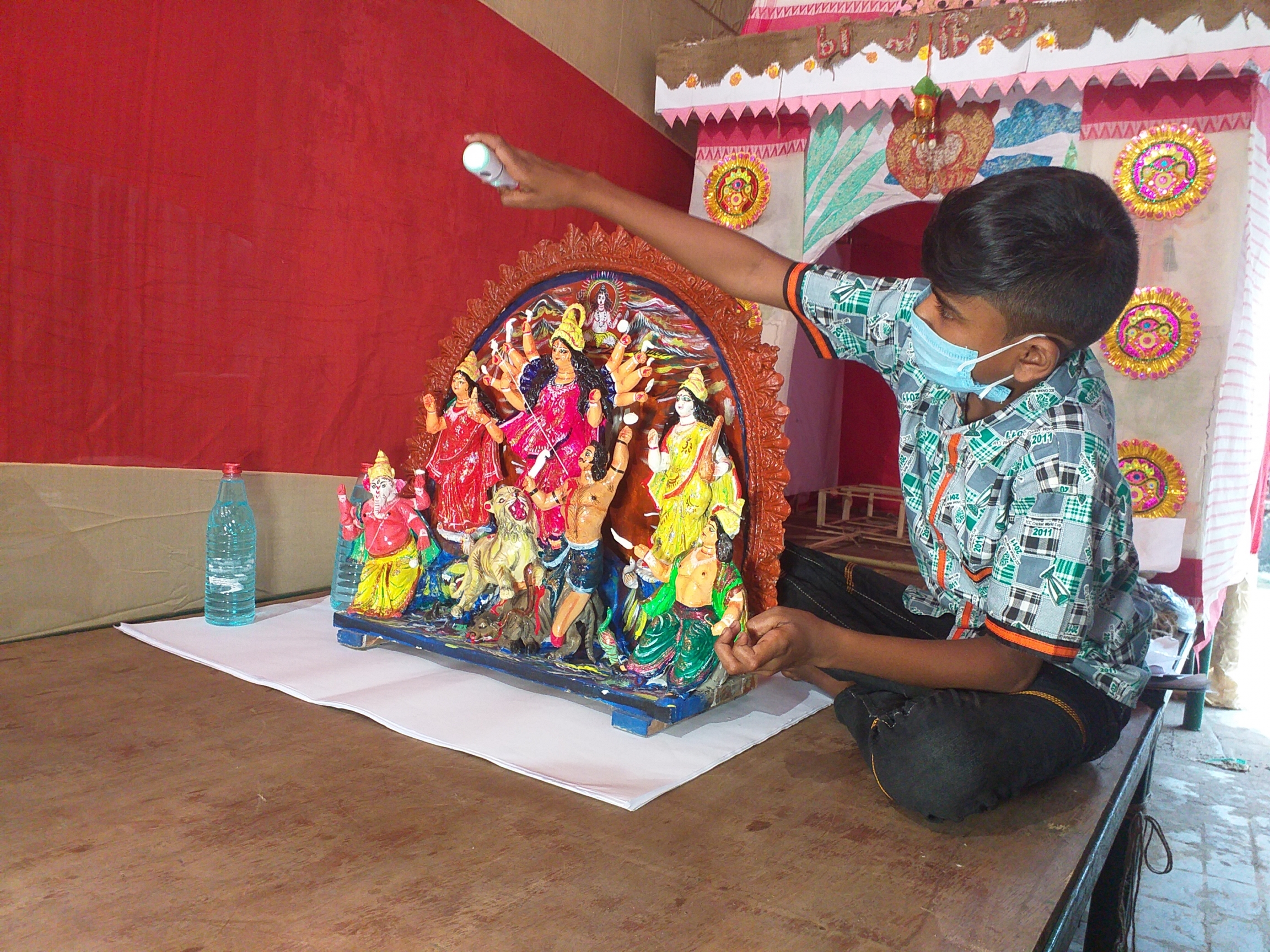 Durga sanitization — a sign of COVID-19 times, Kolkata, India, October 2020. A little boy sanitizes a small idol.