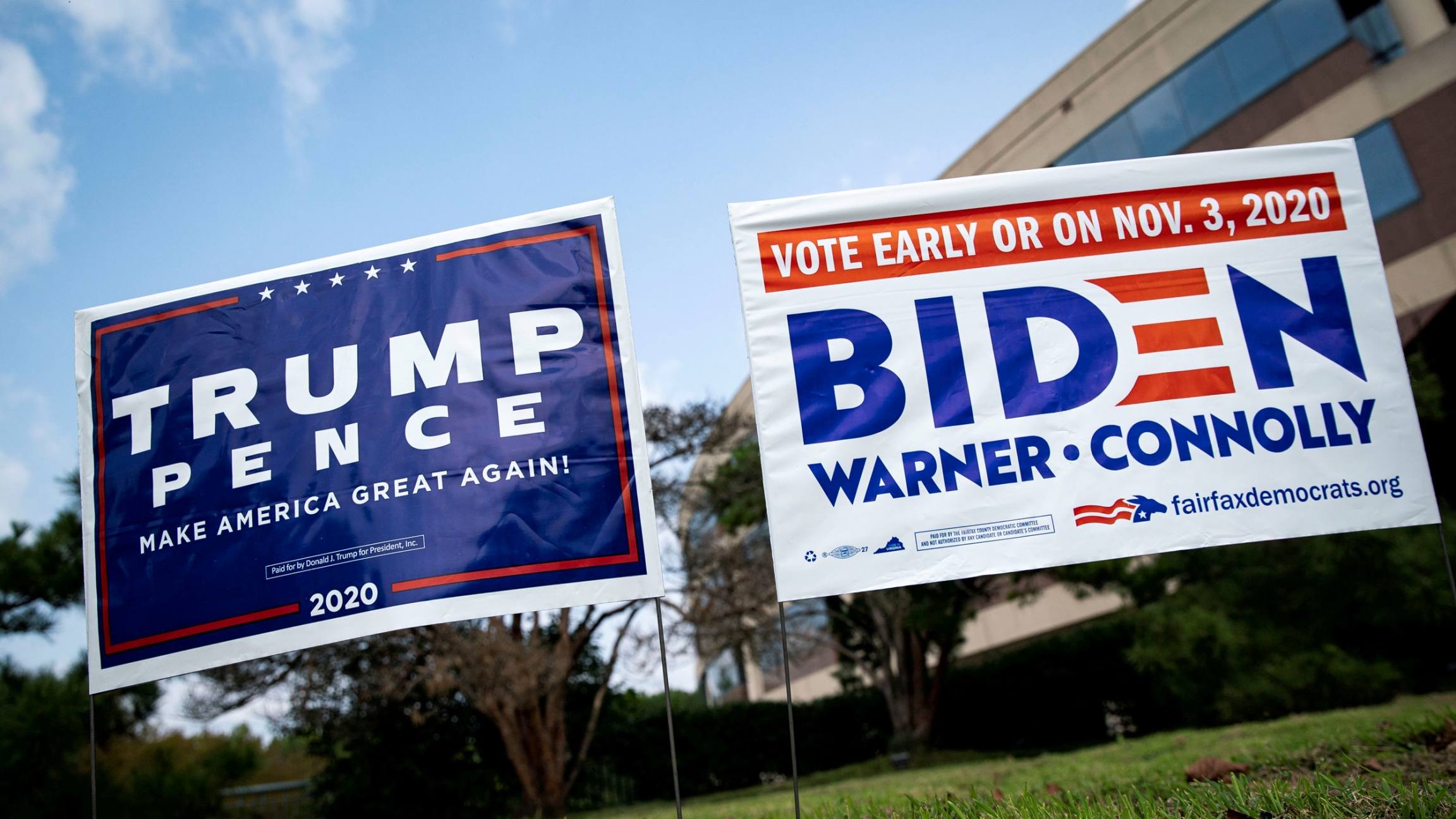 Yard signs supporting US President Donald Trump and former Vice President Joe Biden are seen outside of an early voting site at the Fairfax County Government Center in Fairfax, Virginia, Sept. 18, 2020. Two political yards signs are shown side-by-side — a mostly blue-colored Trump sign and a white with blue lettering Biden sign.