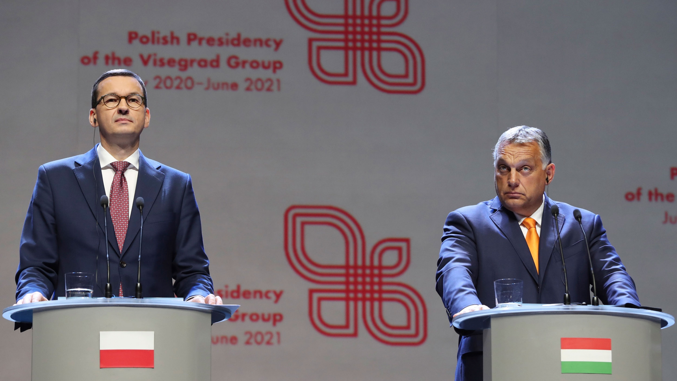 Viktor Orban (R) prime minister of Hungary and Polish Prime Minister Mateusz Morawiecki attend a news conference in Lublin, Poland, Sept. 11, 2020. Viktor Orban (R) prime minister of Hungary and Polish Prime Minister Mateusz Morawiecki are shown both wearing dark suits and standing behind podiums, each with their respective country flags on the front.