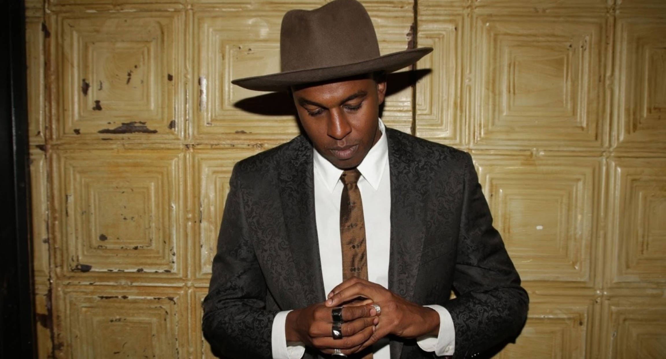 Sudanese American artist Ahmed Gallab who performs as Sinkane. Sinkane is shown wearing a suit and wide-brimmed hat.