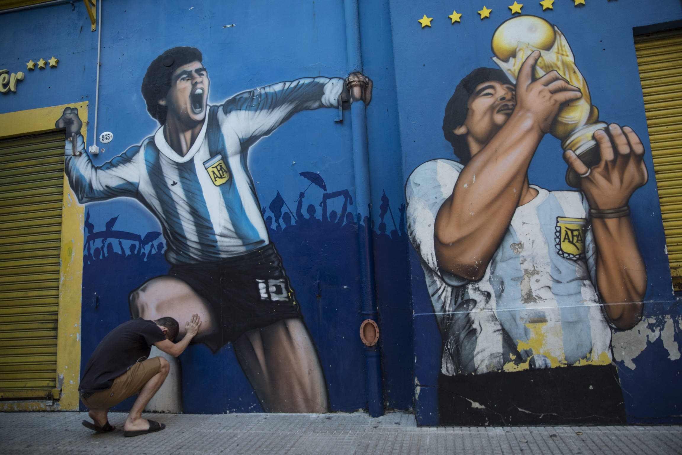 A man prays while touching a painting of Diego Maradona near the Boca Juniors stadium in Buenos Aires, Argentina, Nov. 27, 2020. A man prays while touching a painting of Diego Maradona near the Boca Juniors stadium in Buenos Aires, Argentina, Nov. 27, 2020.