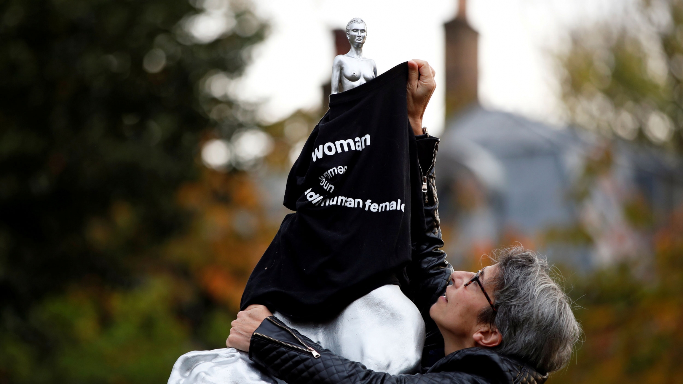A protester covers with a T-shirt the Mary Wollstonecraft statue by artist Maggi Hambling, in Newington Green, London, Britain, Nov. 11, 2020. A woman is shown covering a nude silver statue with a black T-shirt with the word, "woman" printed on it.