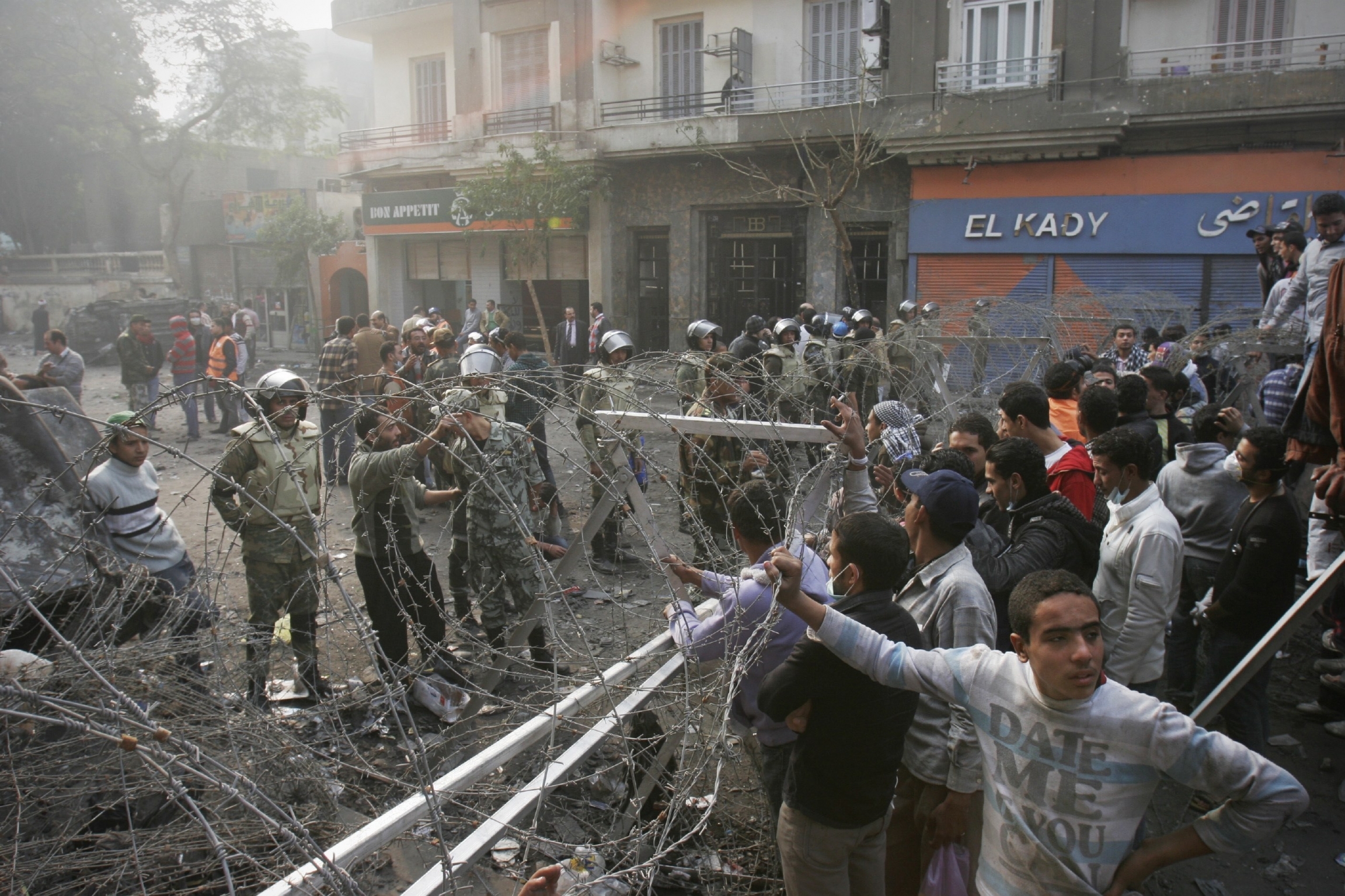 In this Thursday, Nov. 24, 2011 file photo, Egyptian protesters stand behind a barbed wire barricade in Tahrir Square in Cairo, Egypt.