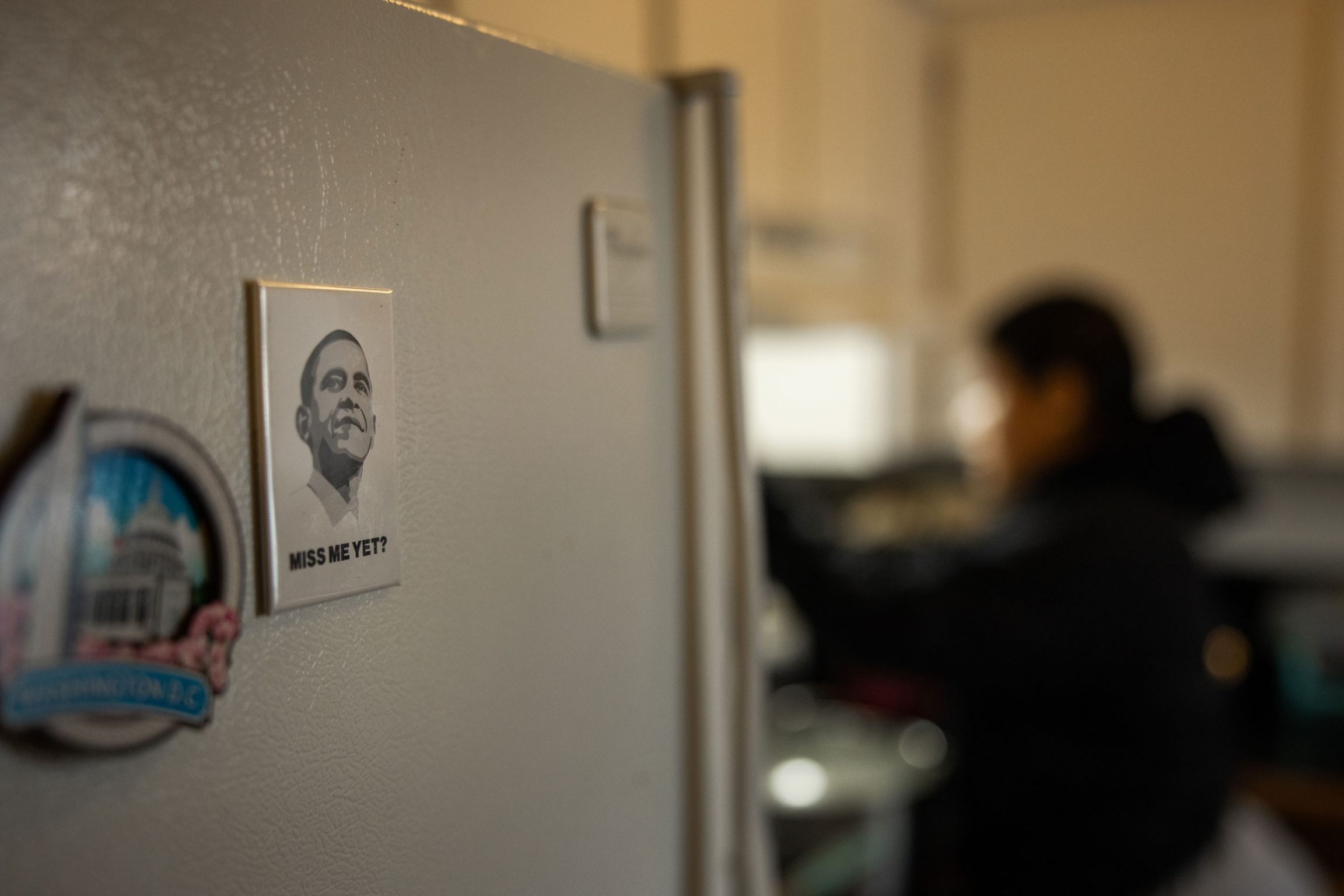 Michelle Aguilar Ramirez cleans the kitchen at her home that she shares with her mom in Spokane, WA. A magnet with a portrait of President Barack Obama is shown with a woman in the distance in soft focus.