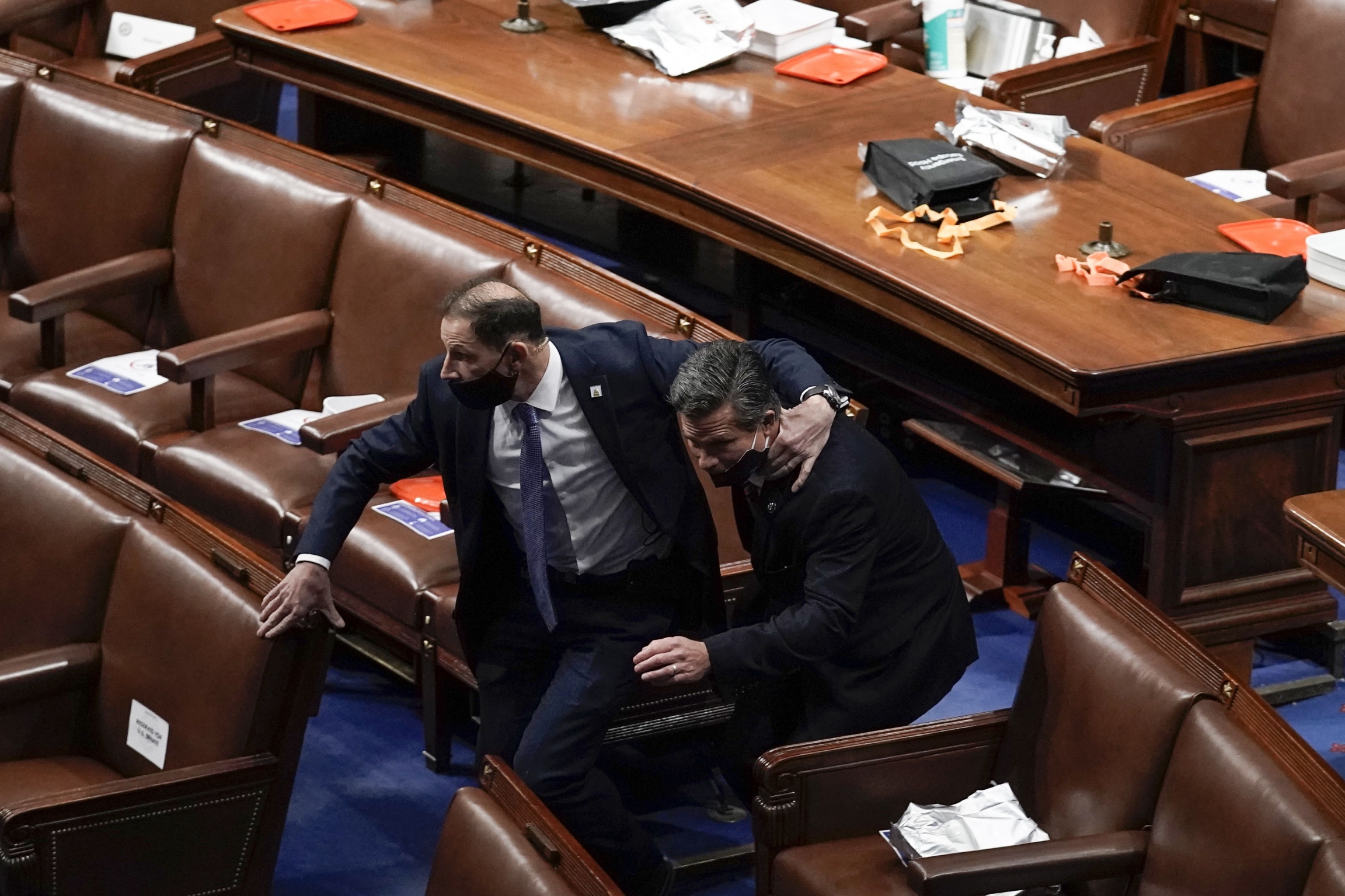 Lawmakers evacuate the floor as a violent mob tries to break into the House Chamber at the US Capitol on Wednesday, Jan. 6, 2021, in Washington. Two men in black suits run to evacuate the floor as a violent mob tries to break into the House Chamber at the US Capitol