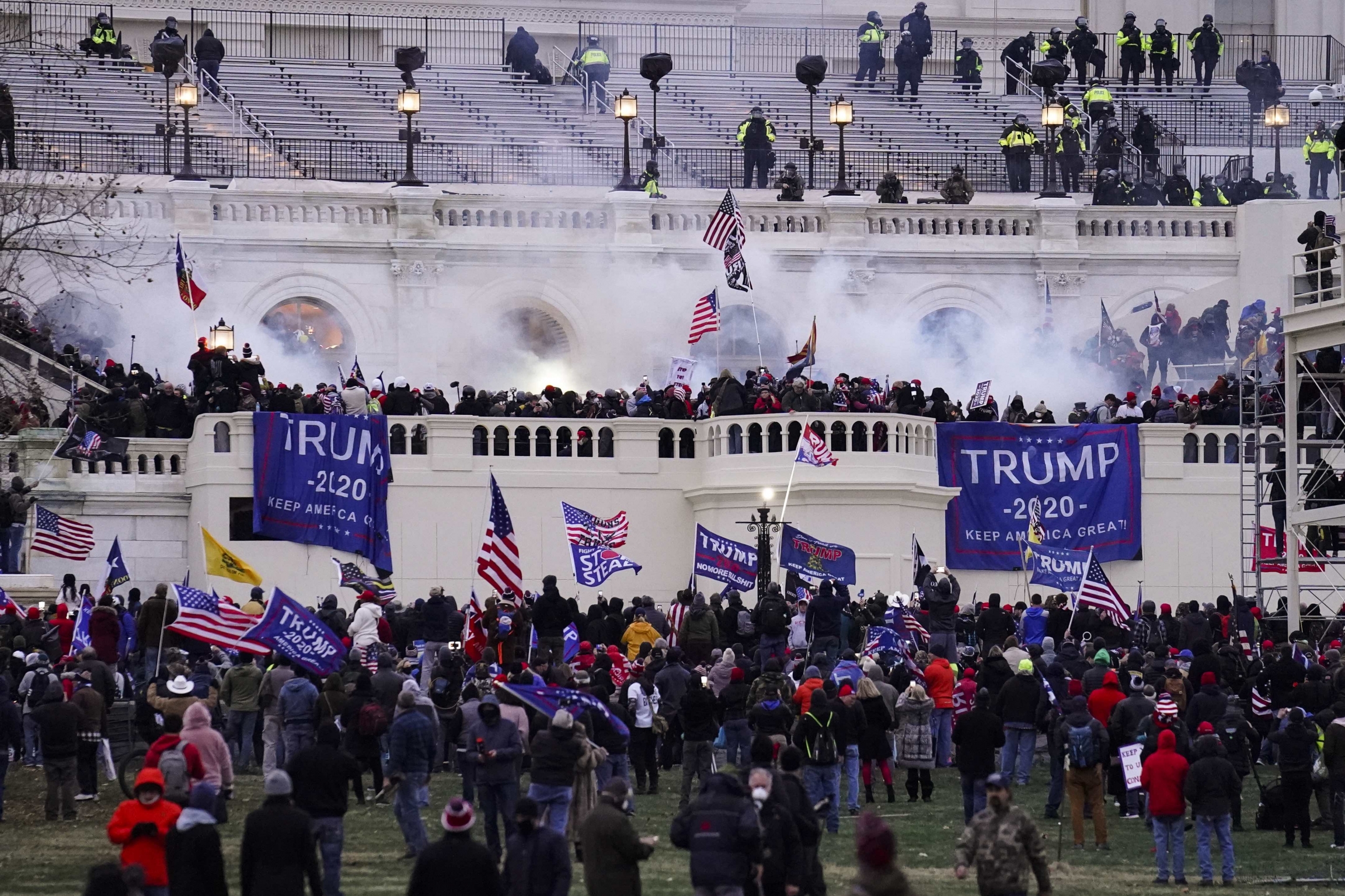 Violent protesters loyal to President Donald Trump storm the Capitol, Wednesday, Jan. 6, 2021, in Washington, DC. A large group of people with flags that read Tump storm the US Capitol building.