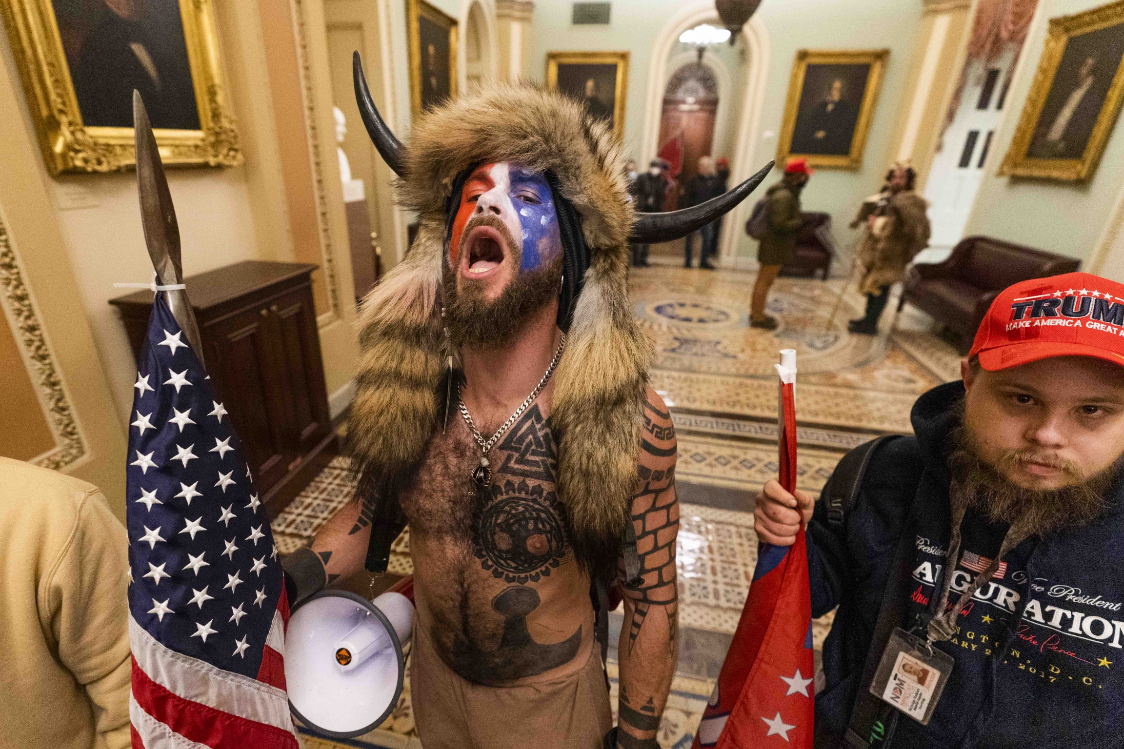A supporter of President Donald Trump chants outside the Senate chamber inside the Capitol, Wednesday, Jan. 6, 2021, in Washington, DC. A supporter of President Donald Trump wearing horns and animal skins on his head chants outside the Senate chamber inside the Capitol, Wednesday, Jan. 6, 2021, in Washington, DC.