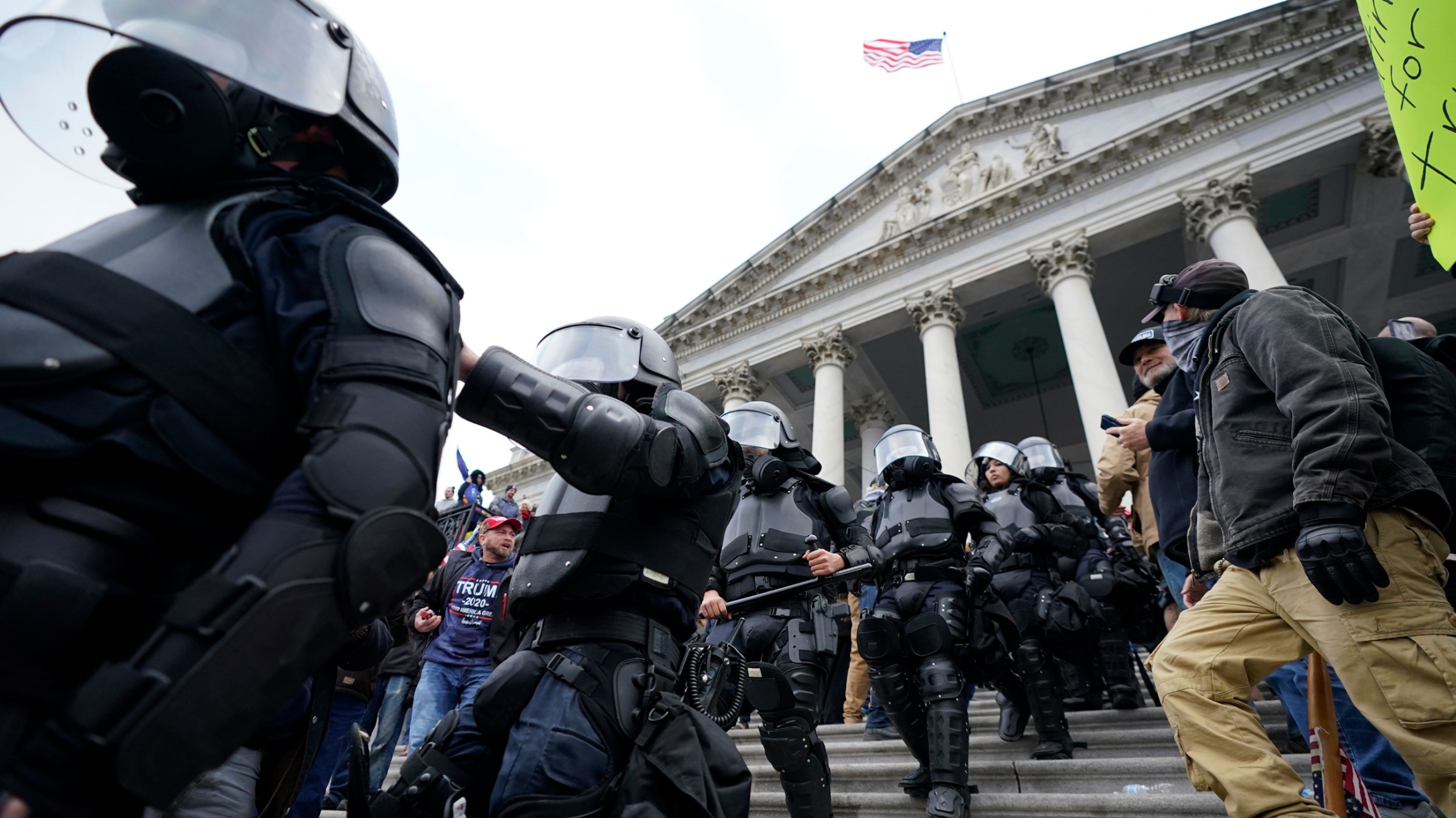 Police in riot gear walk out of the Capitol building in Washington. As Congress prepared to affirm President-elect Joe Biden's victory, thousands of people gathered to show their support for President Donald Trump, Jan. 6, 2021. A line of police are shown walking down the Capitol building staircase dressed in black armor with helmets.