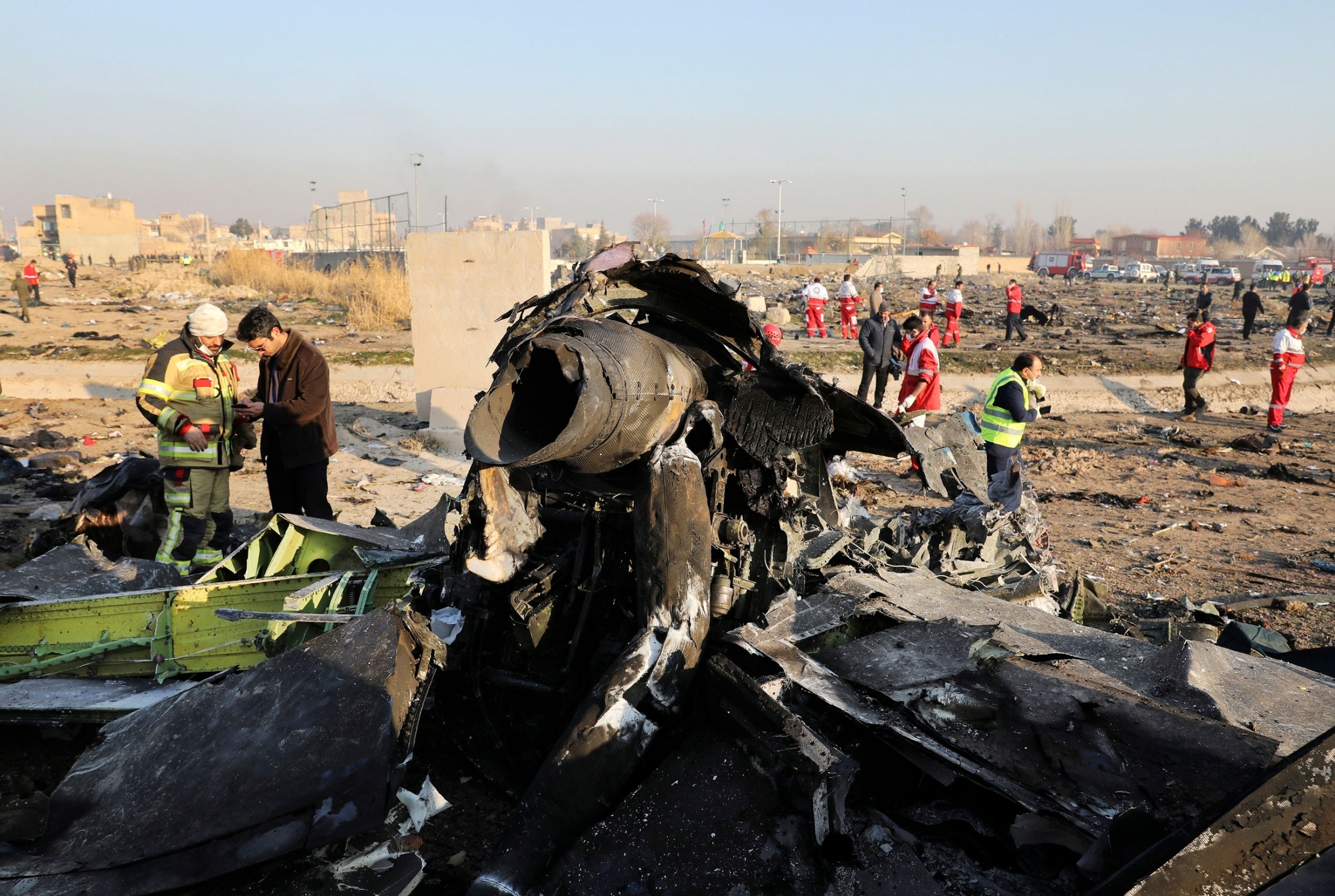Debris litters the scene where a Ukrainian plane crashed in Shahedshahr southwest of the capital Tehran, Iran, Jan. 8, 2020. The charred remains of a passenger aircraft is shown with several inspectors shown on the scene in the distance.