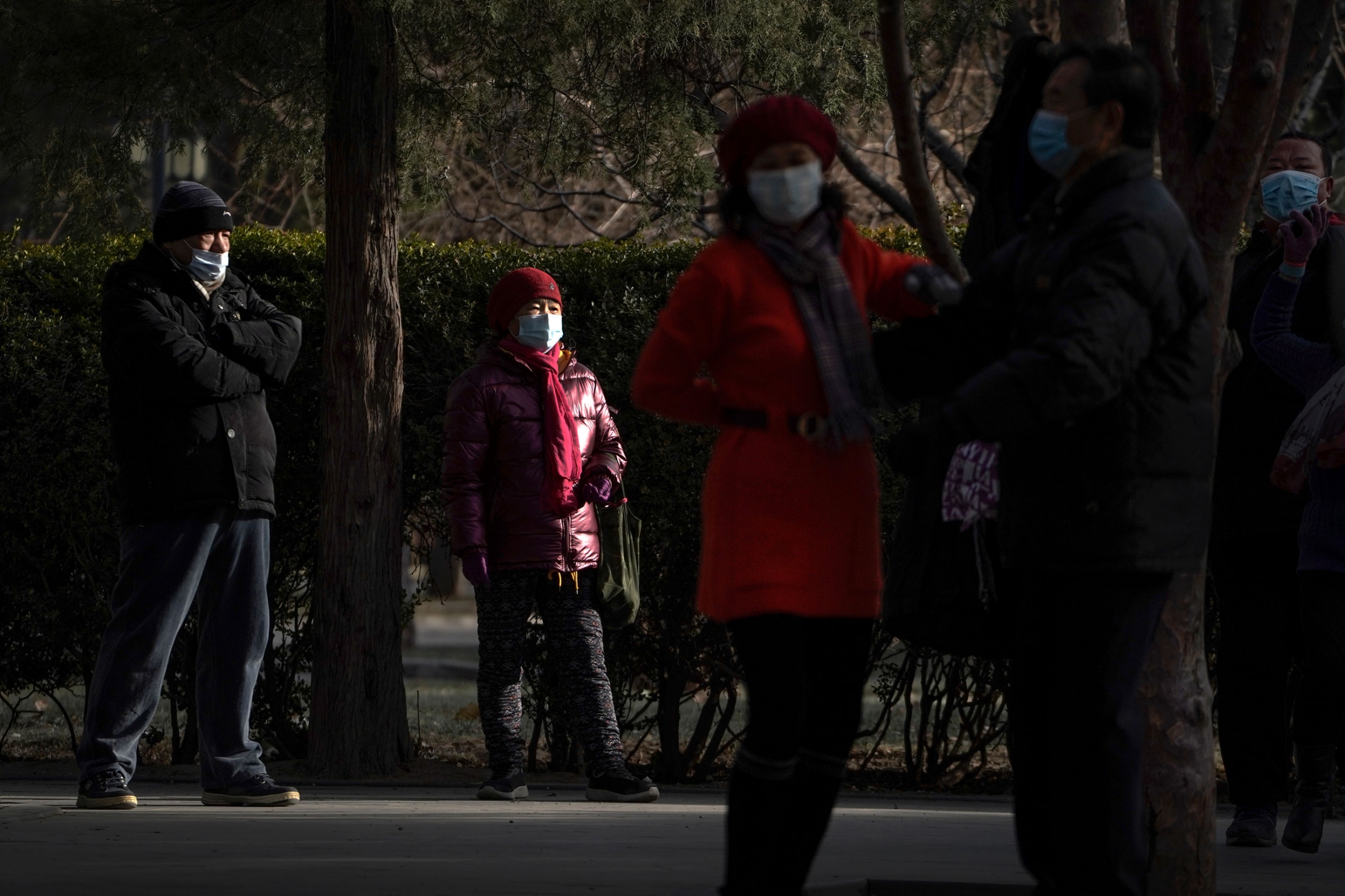 People wearing face masks to help curb the spread of the coronavirus at a public park in Beijing, Jan. 12, 2021. Several people are shown standing in a park and wearing face masks and winter jackes=ts.