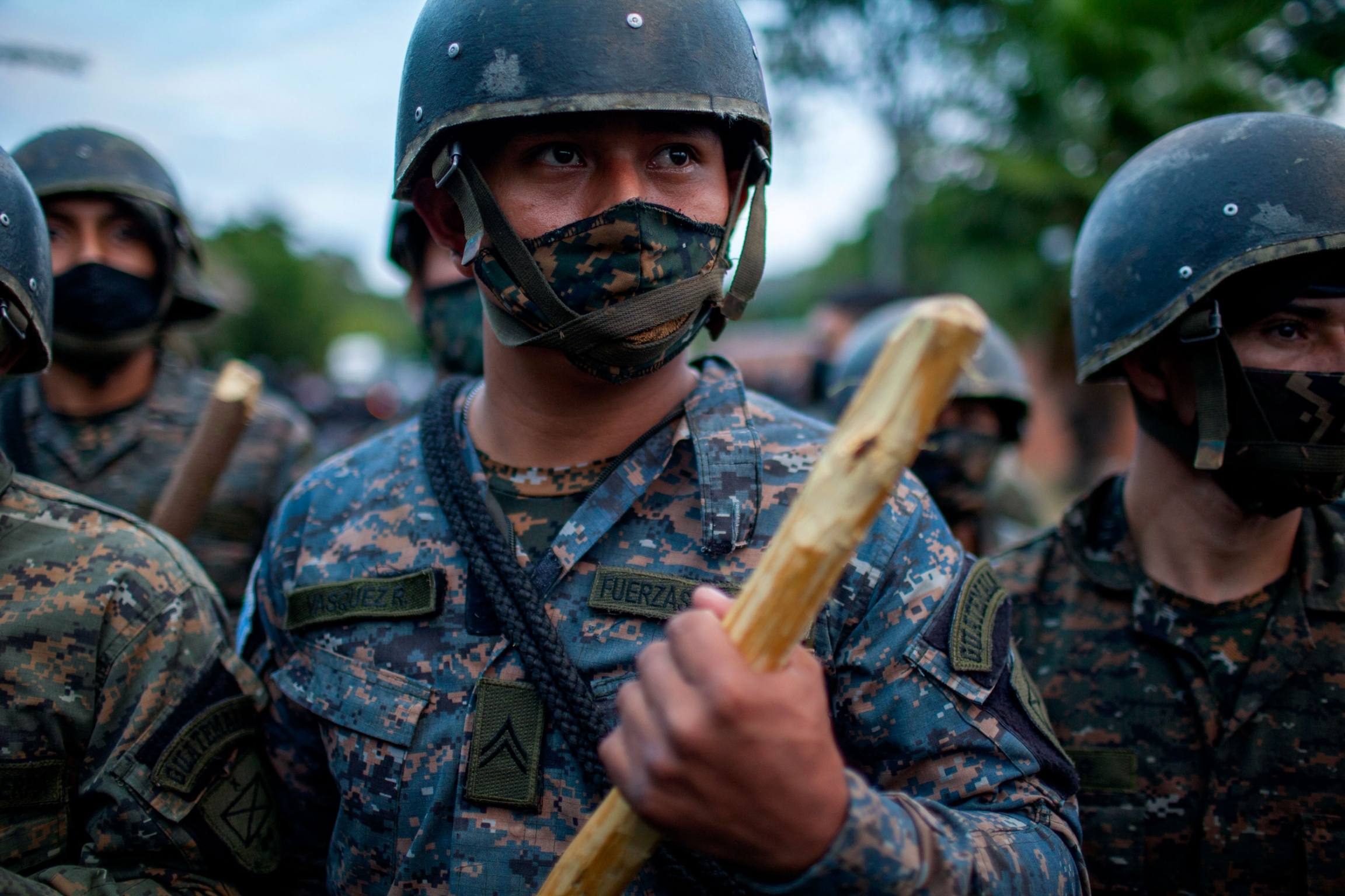 Guatemalan soldiers block part the passage of Honduran migrants in their bid to reach the US border, in Vado Hondo, Guatemala, Jan. 17, 2021. A close-up photograph shows several soldiers wearing helmets and fatigues while holding wooden clubs.
