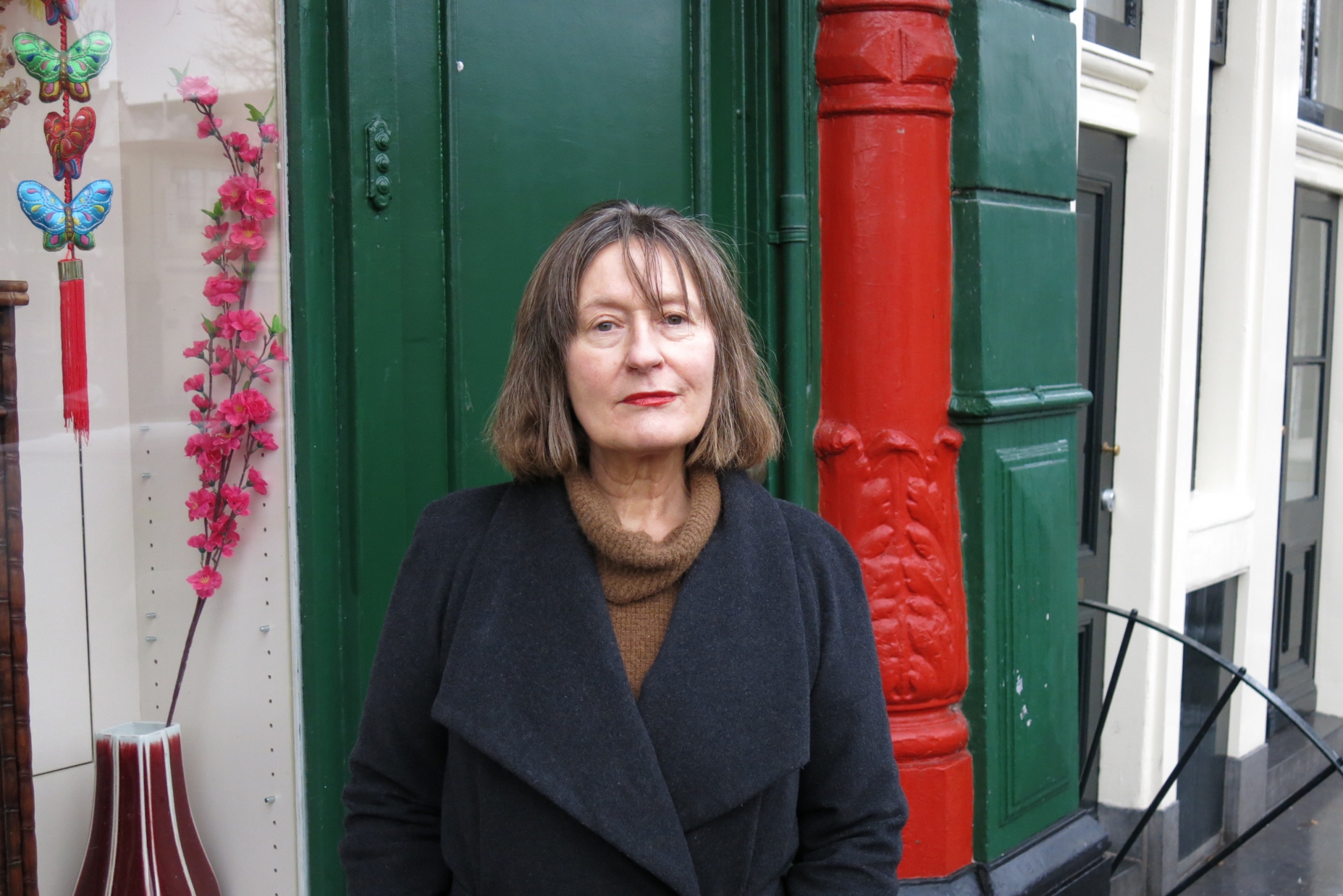 Bernadette de Wit lives on the edge of De Wallen, Amsterdam's red-light district. A woman stands before a green door with a red-painted pillar.