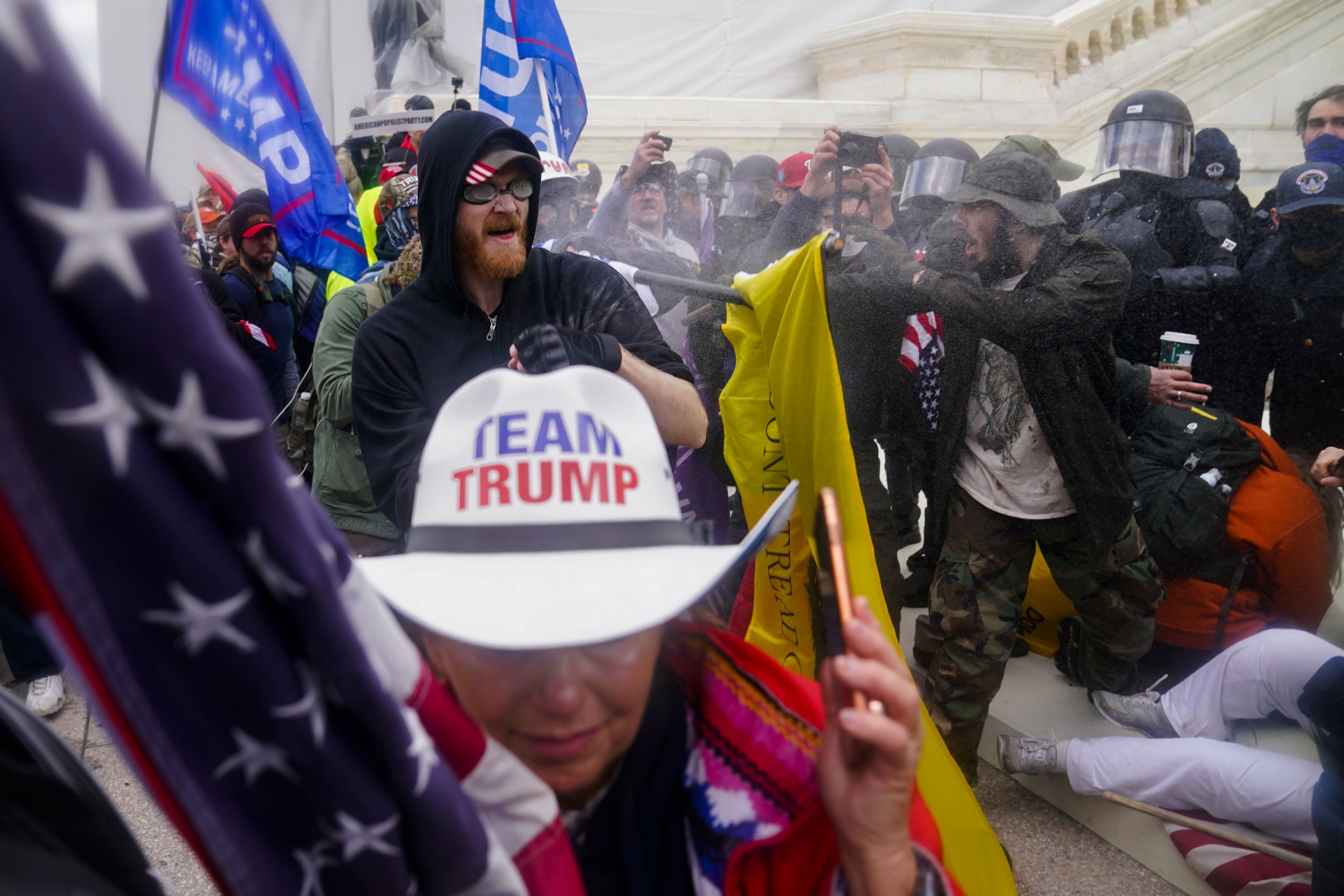 Rioters loyal to President Donald Trump try to break through a police barrier at the Capitol in Washington, Jan. 6, 2021. Several people wearing pro-Trump paraphernalia are shown outside of the US Capitol building with police wearing helmet and face guards shown opposite.