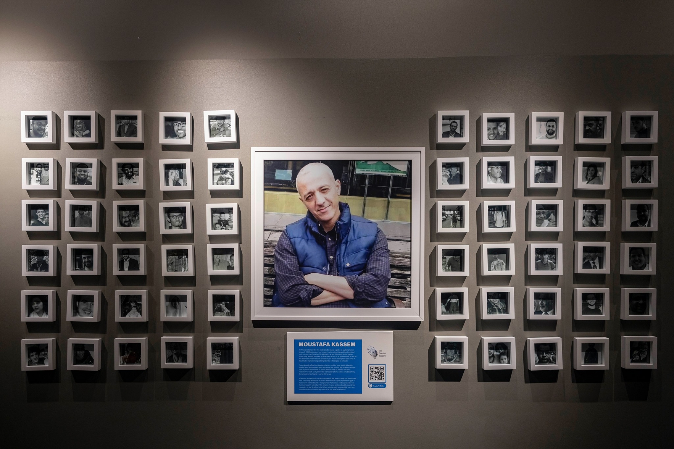 A memorial shows a photo of a man surrounded by several other frames in a gallery. 