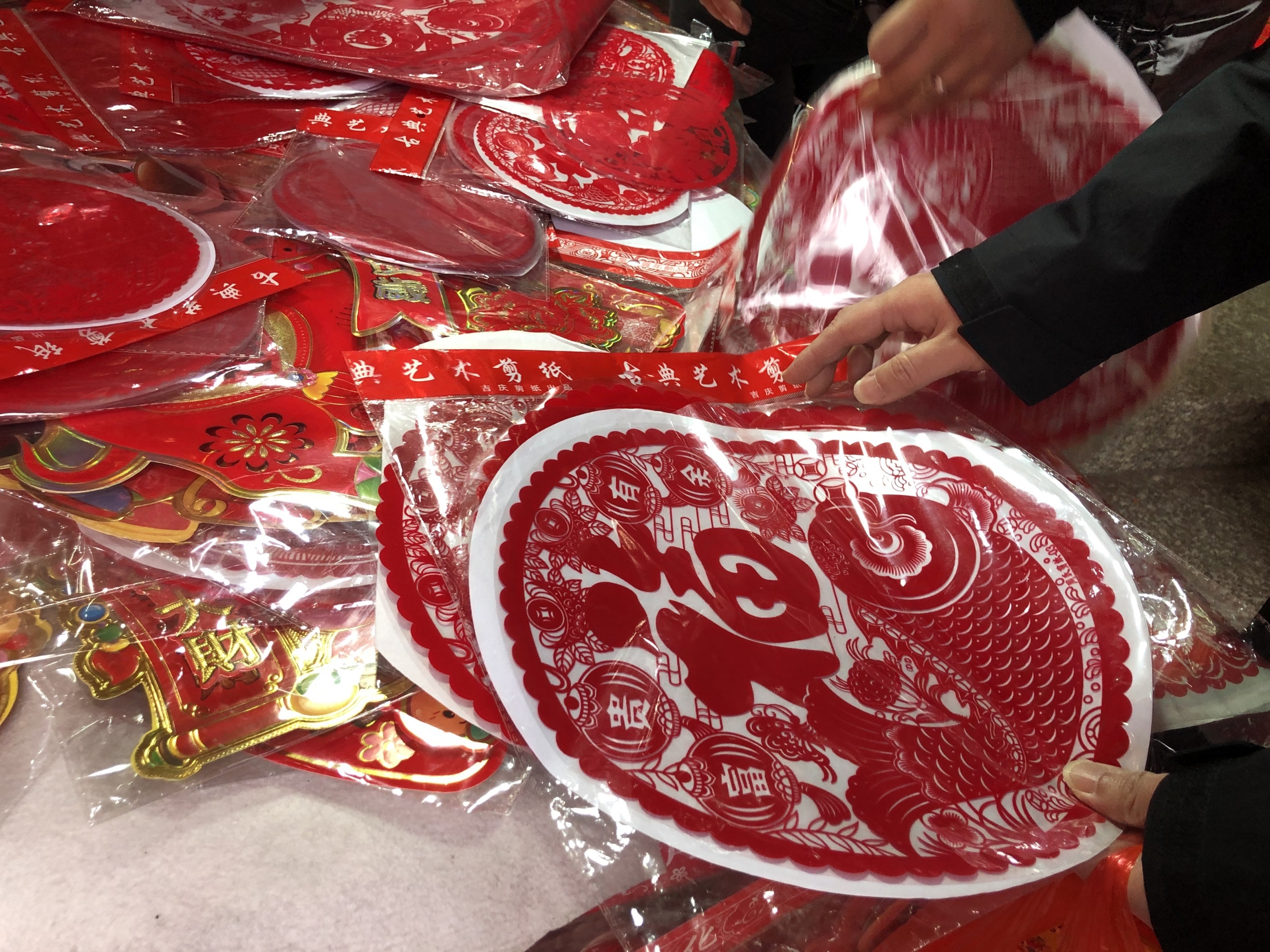 The Chinese government hasn’t actually forbidden holiday travel this year, but they’re strongly discouraging it. So, many people are staying put and finding other ways to celebrate the Chinese New Year — like with red decorations and the like sold in Shan