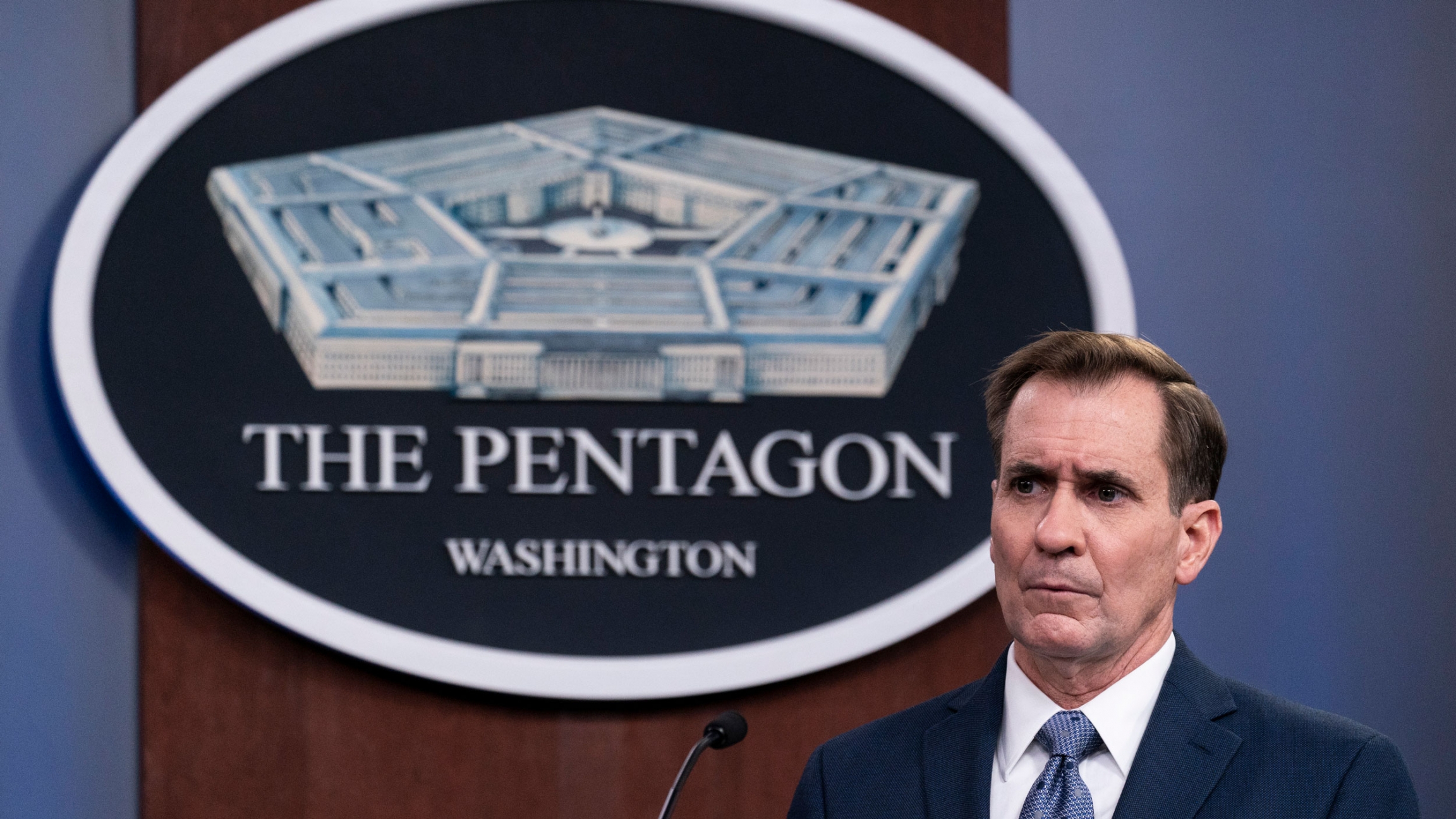 Pentagon spokesman John Kirby speaks during a media briefing in Washington, Feb. 17, 2021. Pentagon spokesman John Kirby is shown wearing a dark blue suit and standing behind a microphone with the logo for the Pentagon behind him.