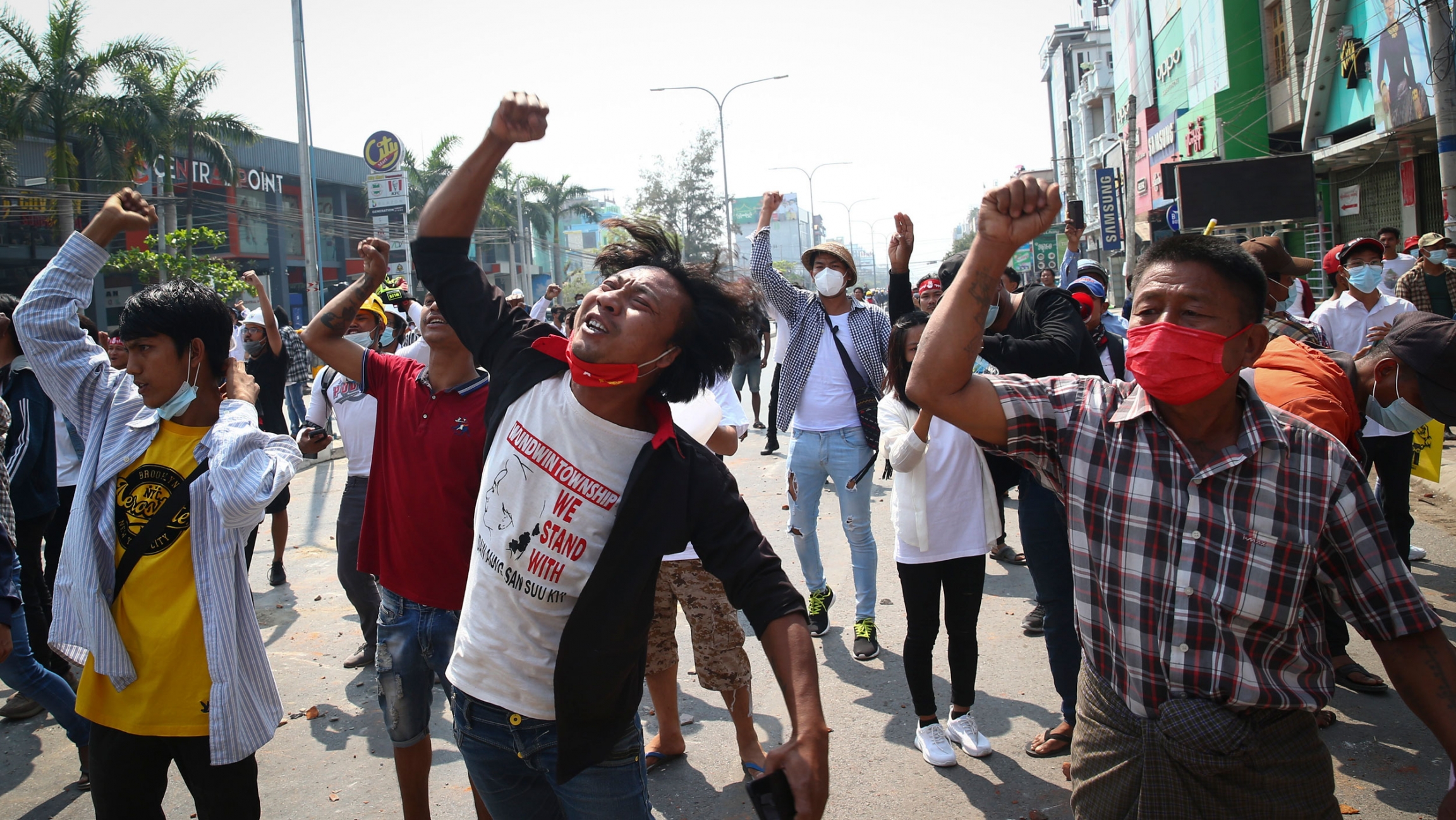 Protesters shout slogans during a protest against the military coup in Mandalay, Myanmar, Feb. 28, 2021. A large crowd of people are shown marching in the street, many with their first raised in the air.