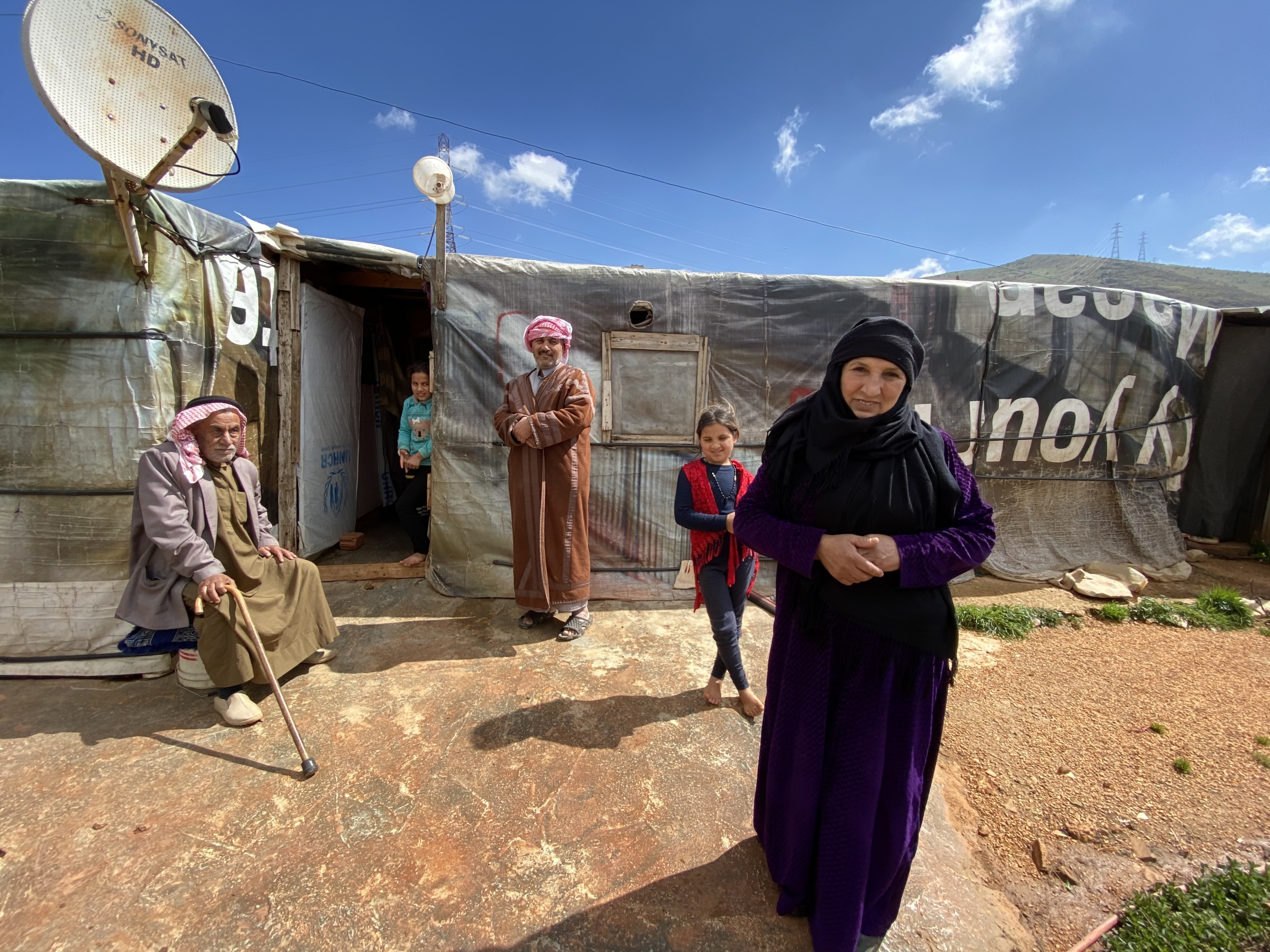 Bashil el-Ahmad in front of her tent with her family. The mountains behind mark the Syrian border. 