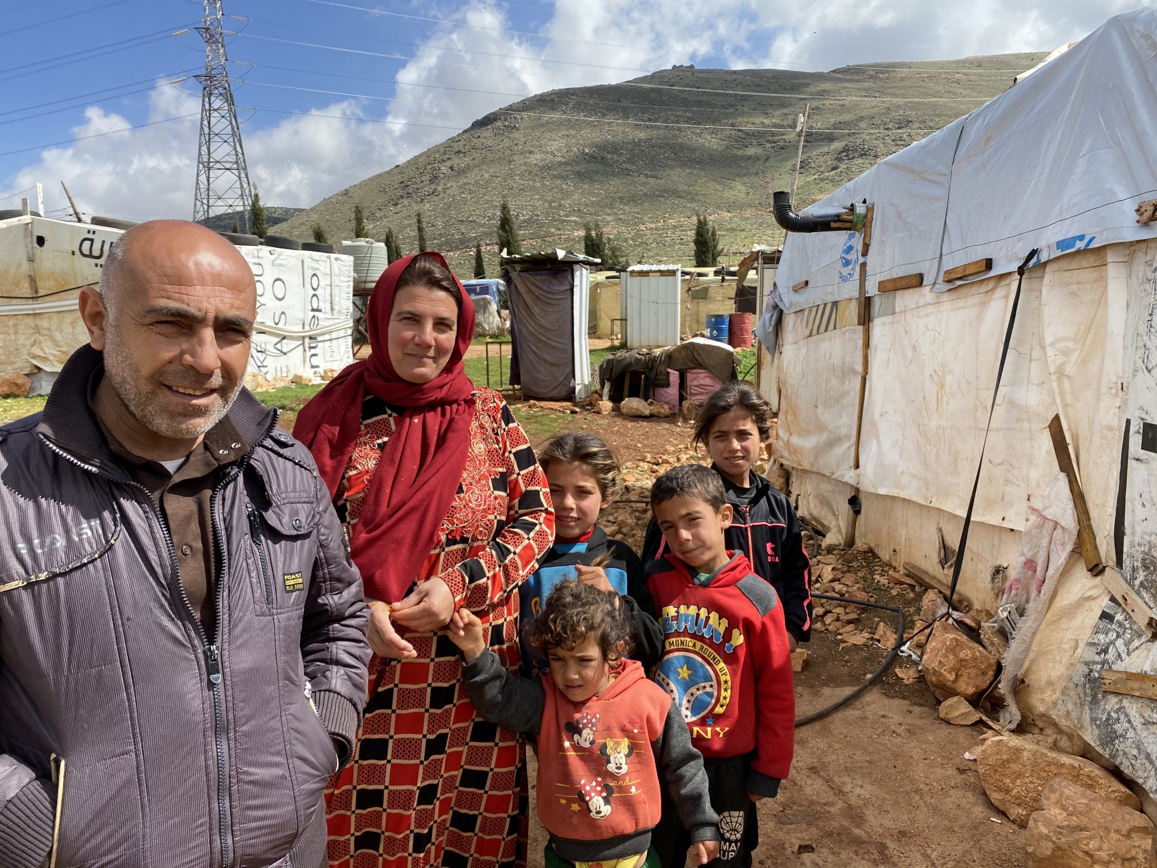 Ali Hamoud stands in front of his tent with his family. The mountains behind mark the Syrian border. Ali Hamoud stands in front of his tent with his family. The mountains behind mark the Syrian border.