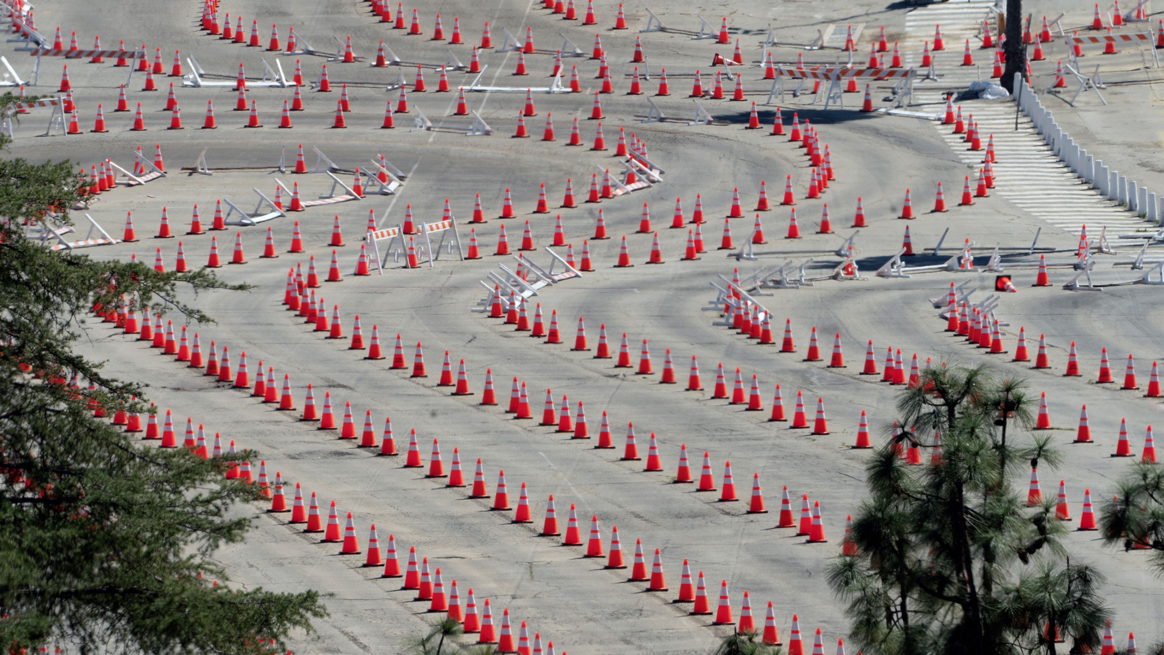 Traffic cones line around the empty parking lot of Dodger Stadium, a mass COVID-19 vaccination in Los Angeles, Friday, Feb. 19, 2021. Several long lines of traffic cones are shown winding around an empty parking lot.